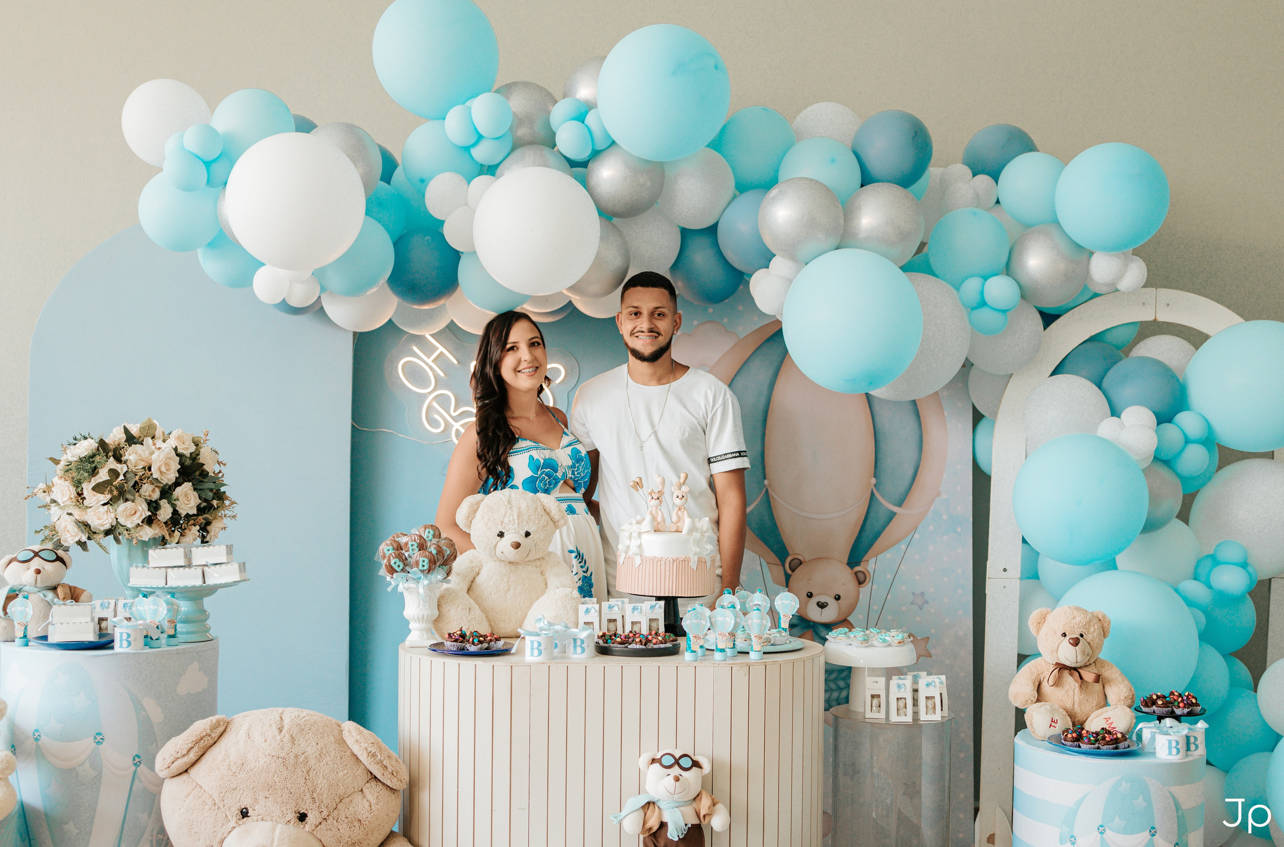Casal posa na decoração azul e branca do chá de bebê em Barra Bonita.