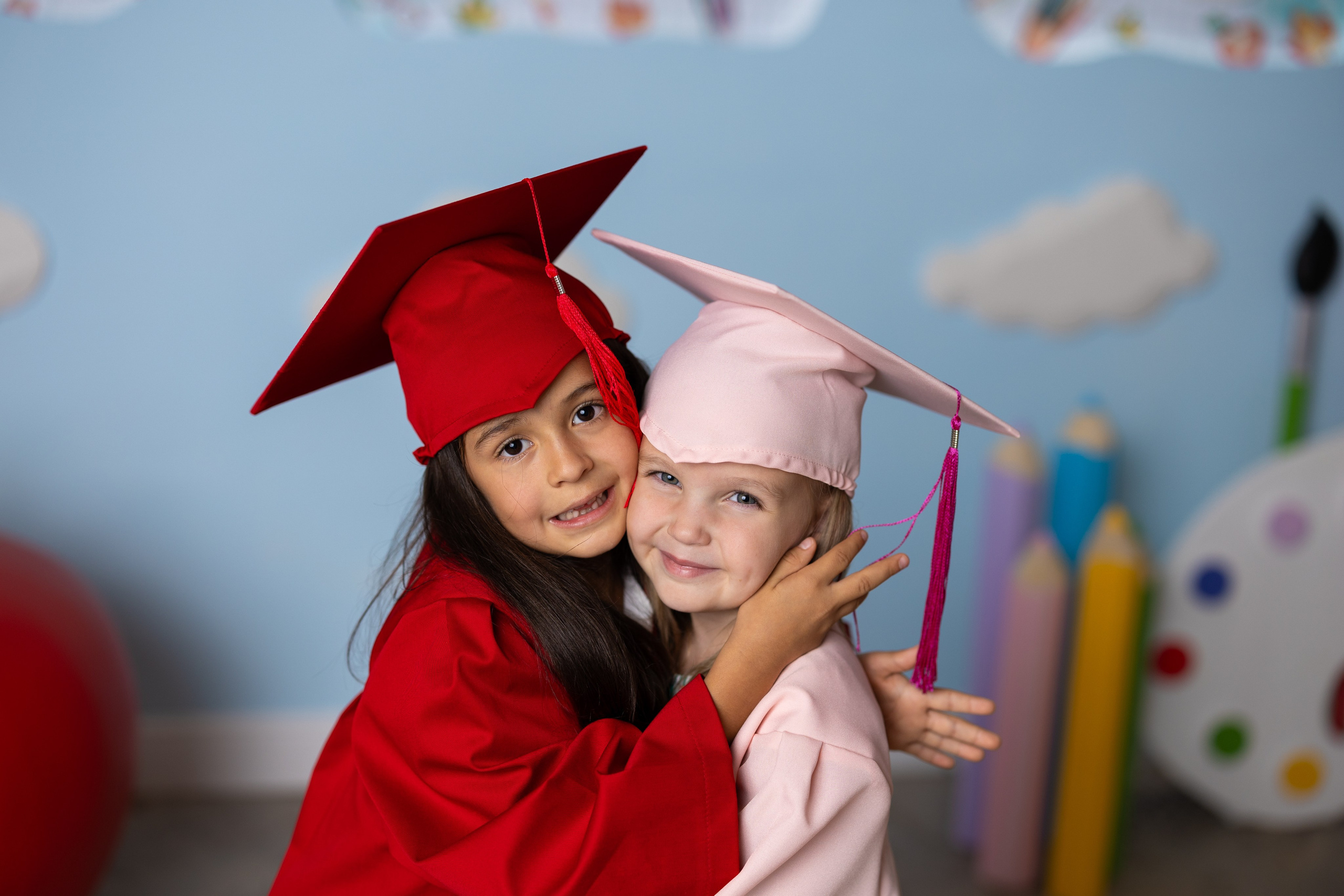 деца с детски тоги и шапки в бордо червено и розово