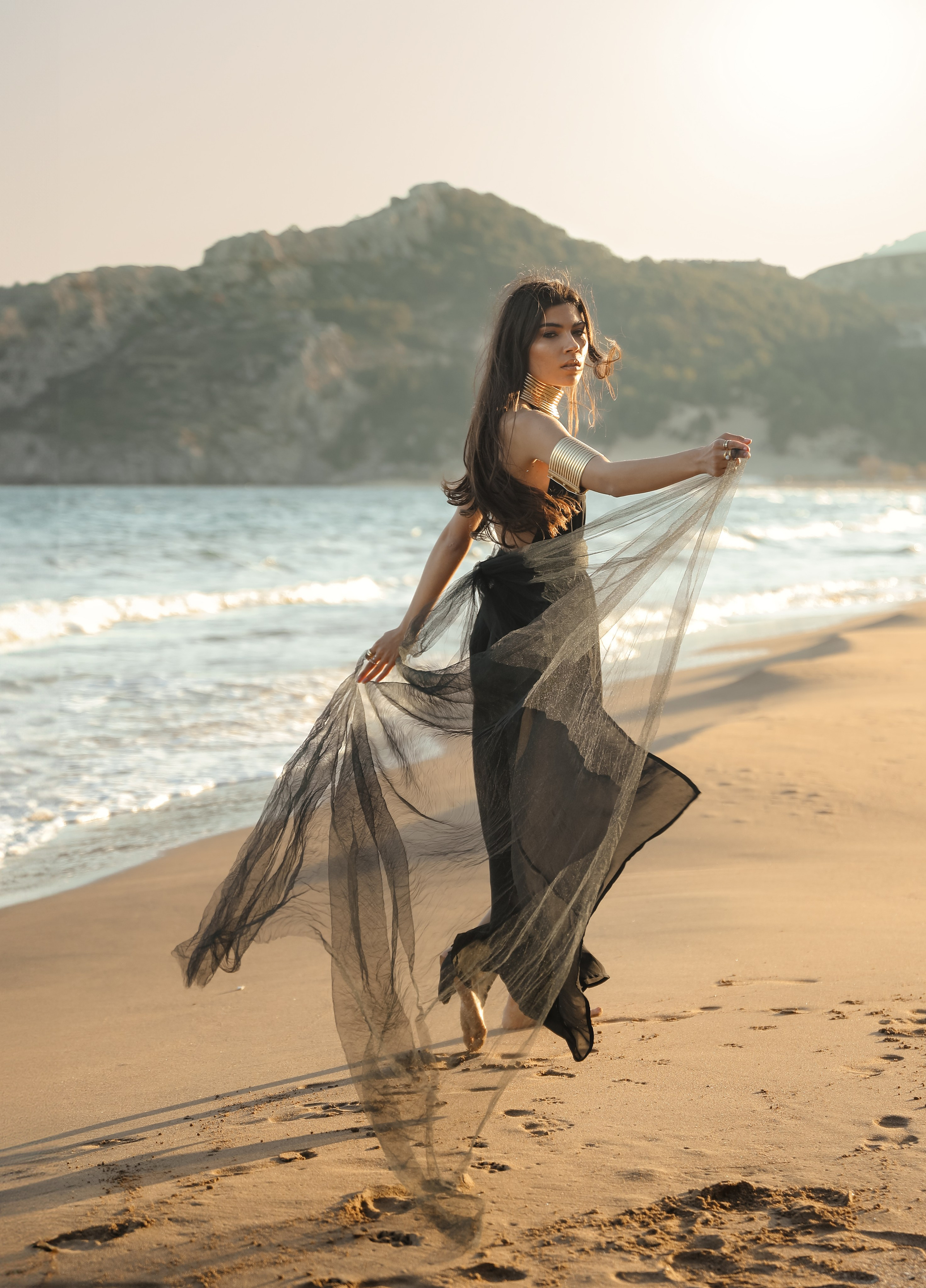 A chic girl in a black dress in the Desert against the setting sun. Rhodes island, Greece