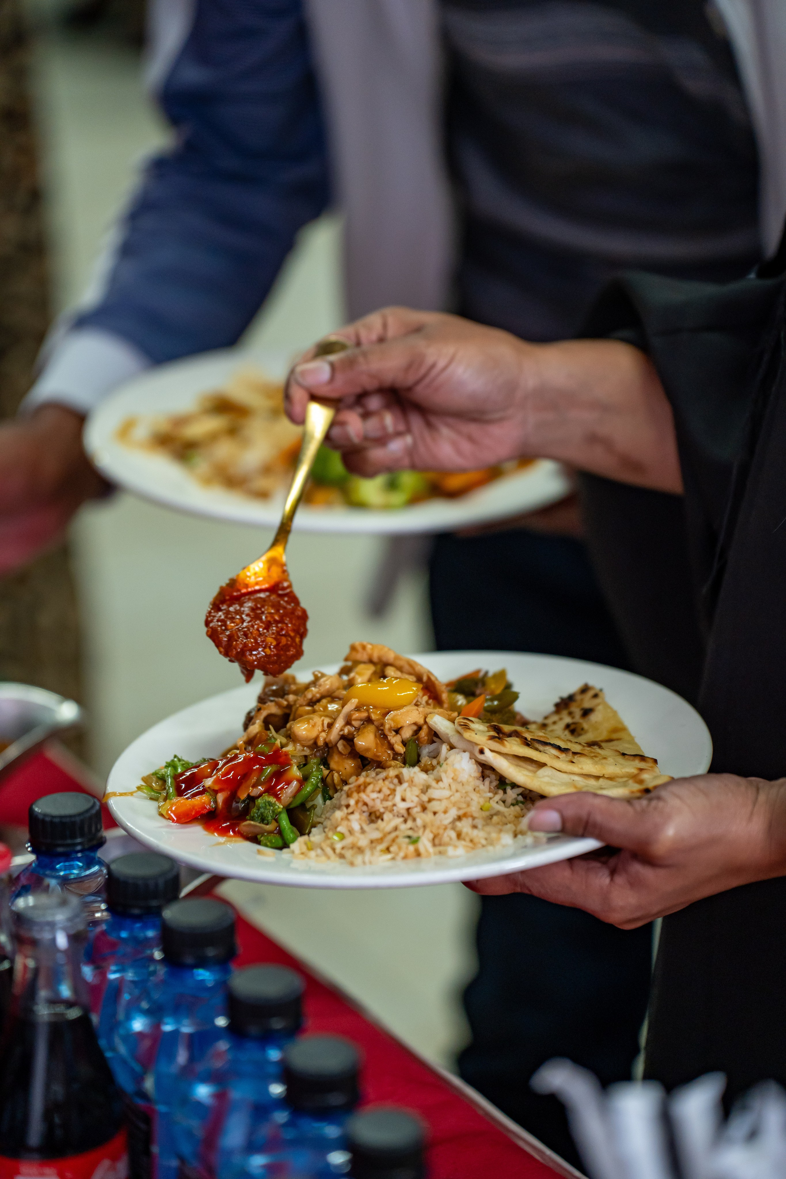 Close-up of guest pouring hot sauce on food at a Nairobi graduation