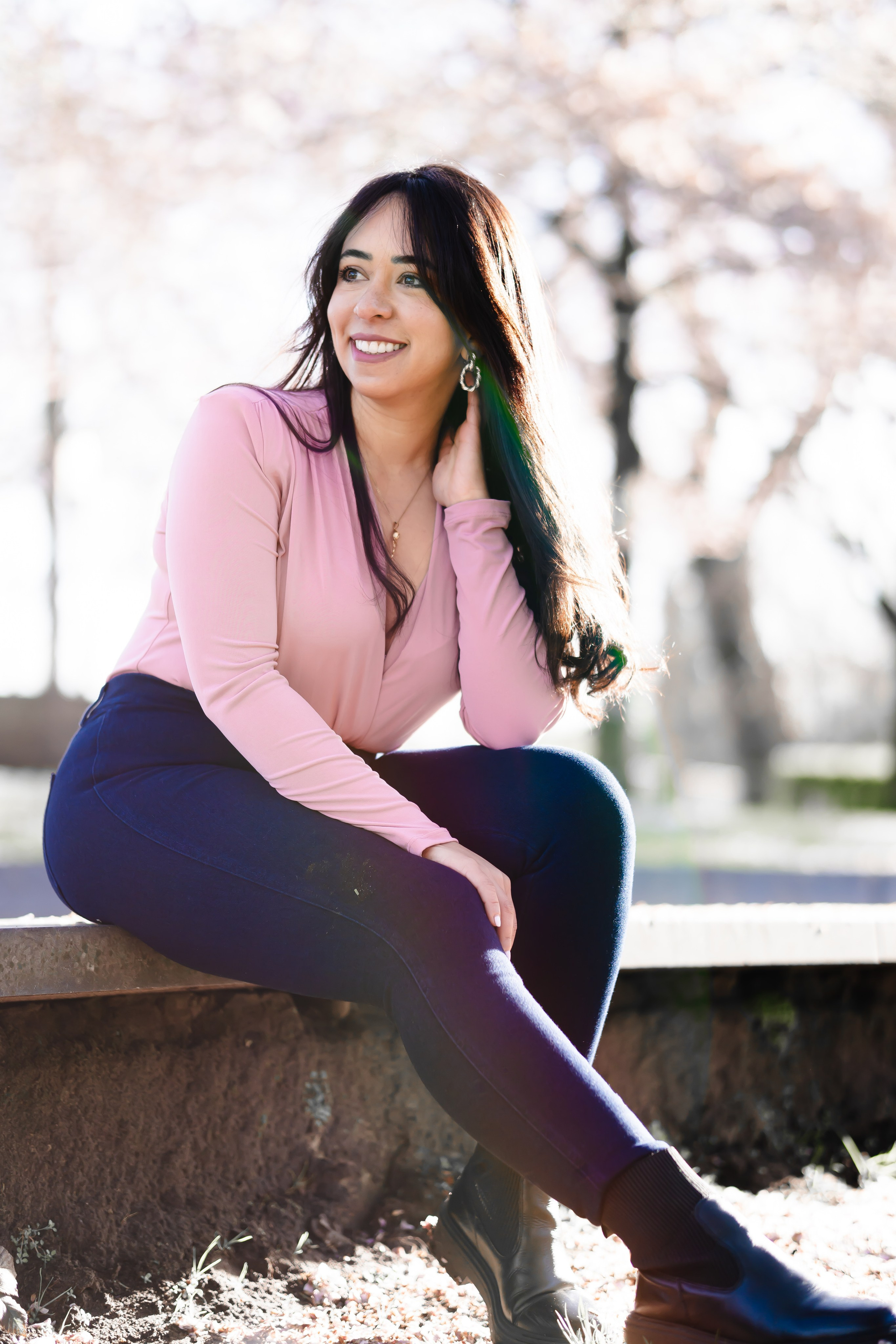 girl sitting on an edge in a cherry blossoms garden