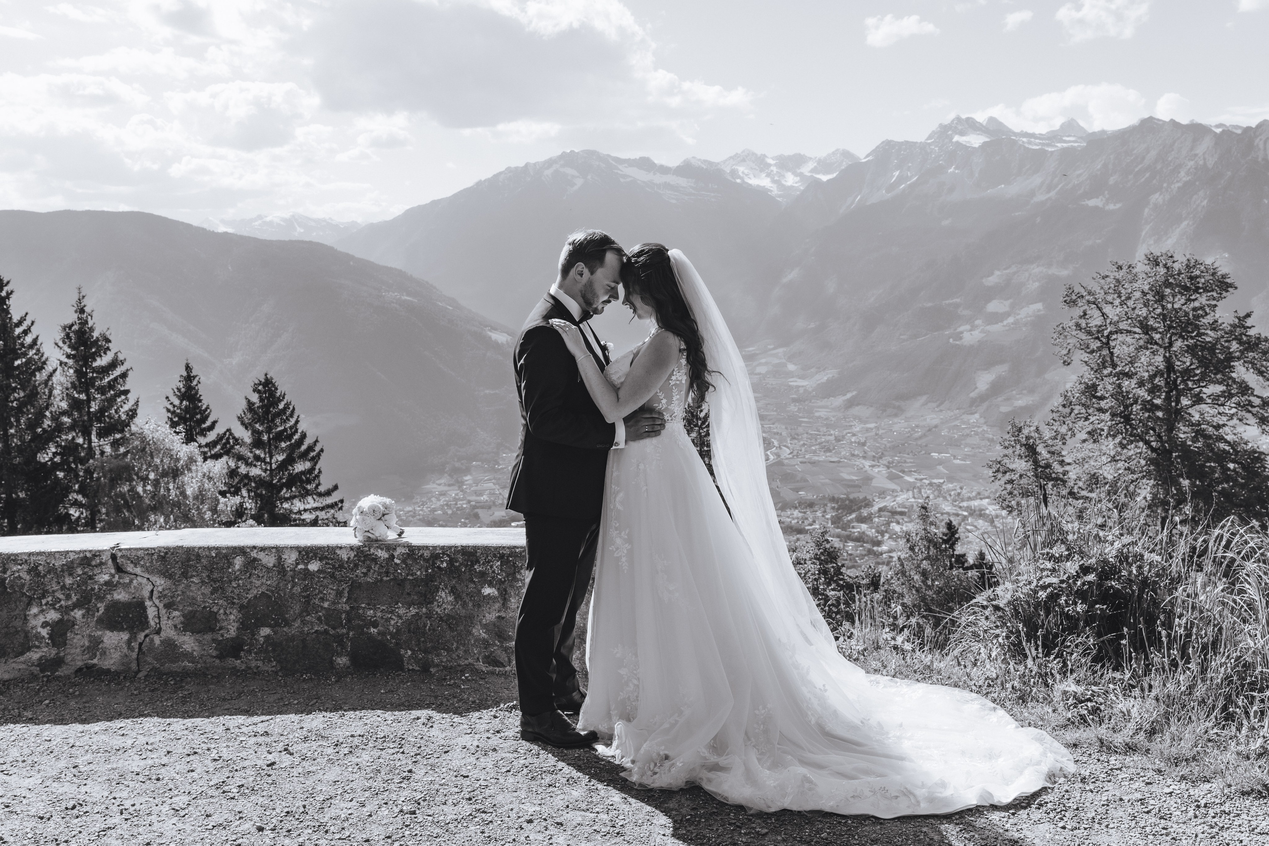 Braut und Bräutigam stehen Stirn an Stirn vor dem beeindruckenden Bergpanorama in Südtirol – ein intimer Moment voller Liebe.