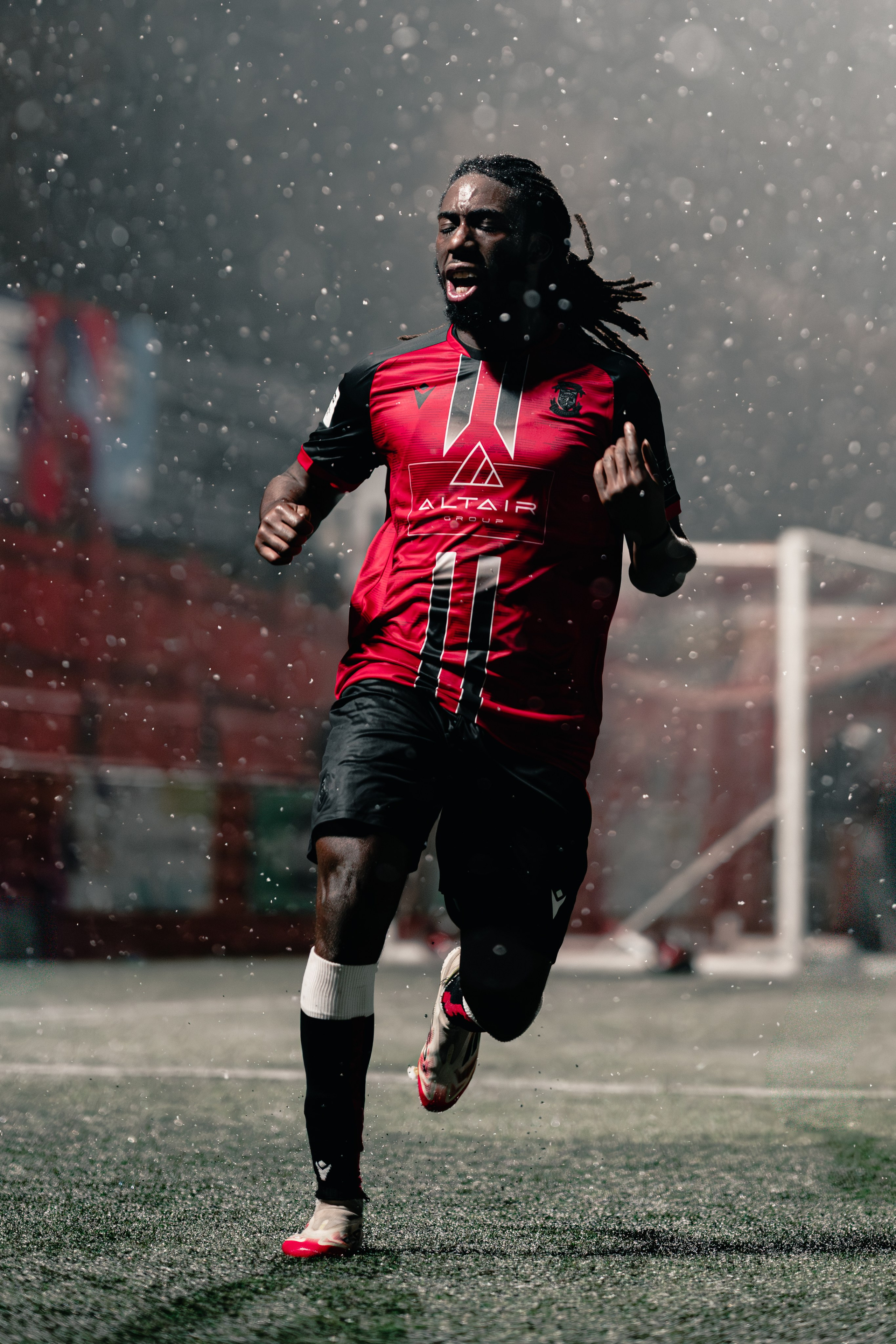 Michael Reindorf of Tamworth FC celebrates under the floodlights in heavy rain during the Birmingham Senior Cup match against Alvechurch at The Lamb Ground, Feb 3 2026.