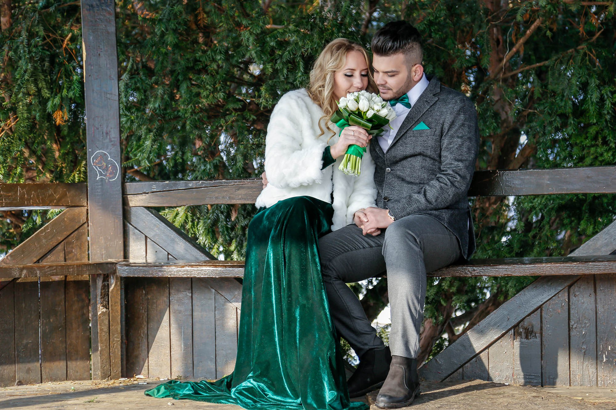 Newlyweds relaxing on a bench inside the gazebo, with the bride smiling happily next to the groom during their photo shoot.