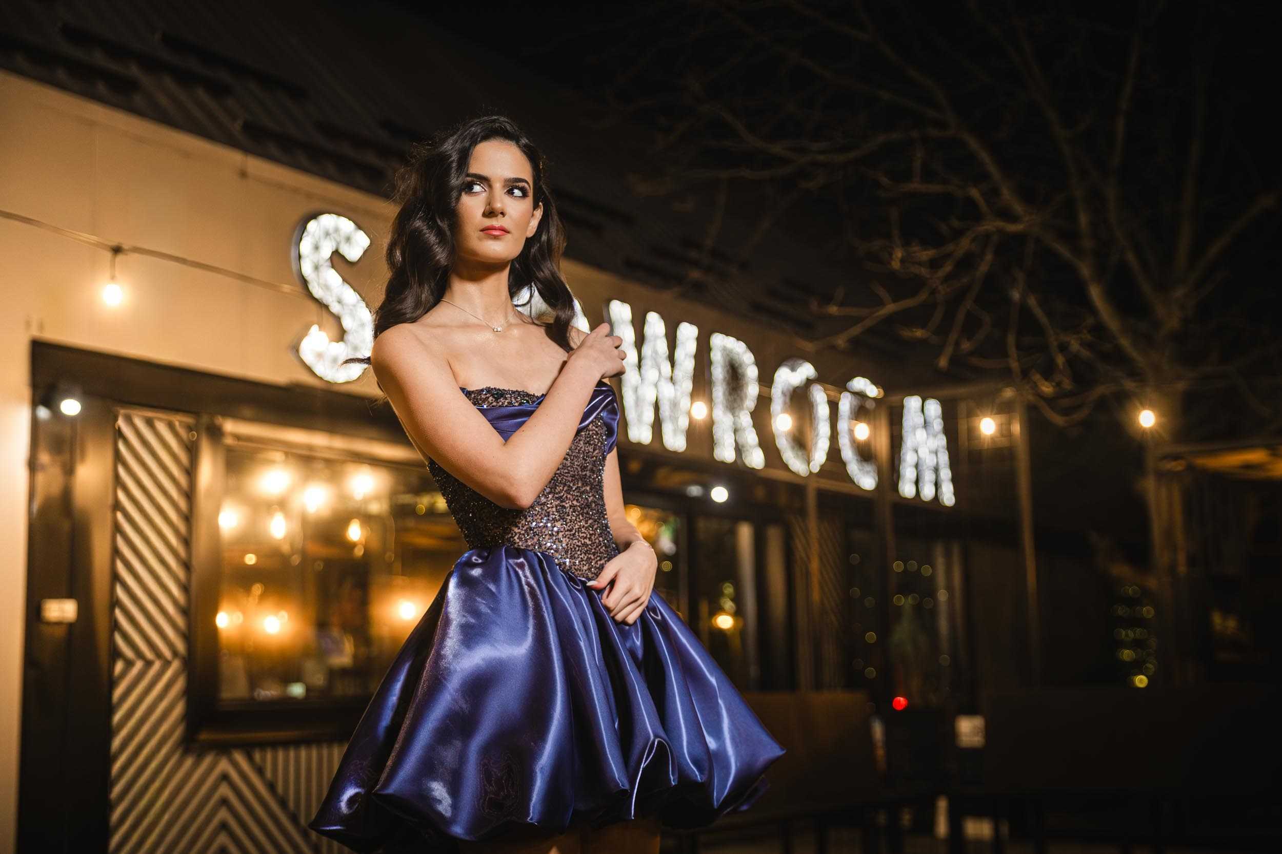 Elegantan portret slavljenice u eksterijeru SHOWROOM-a, profesionalno fotografisanje pod ambijentalnim svetlima Novog Sada.