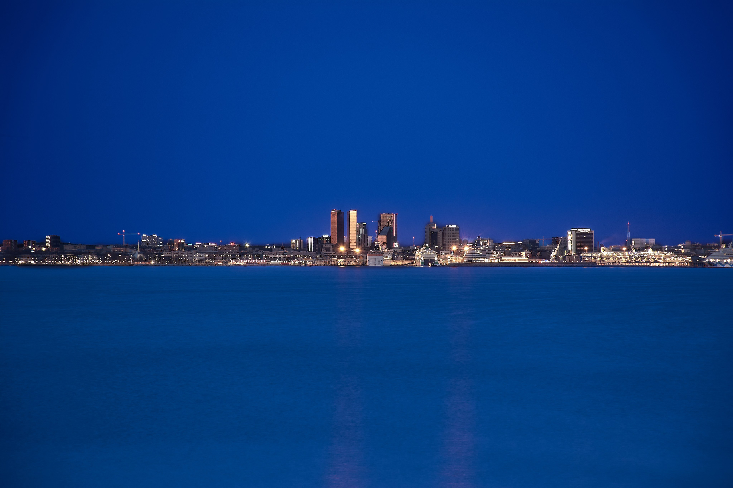Modern city skyline reflected in deep blue bay