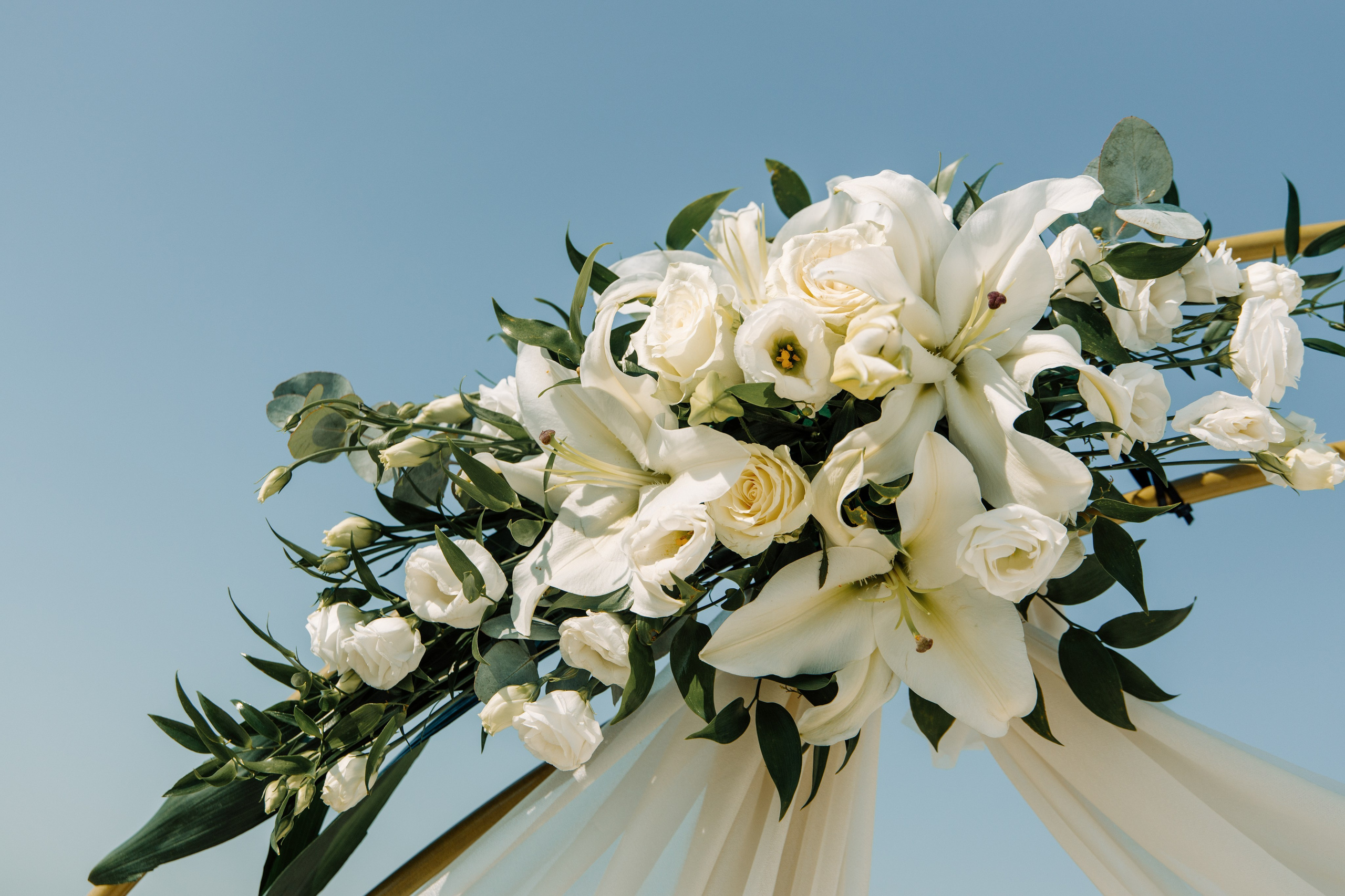 Elegante weiße Hochzeitsblumen schmücken den Traubogen für die Zeremonie am Profitis Ilias in Faliraki auf Rhodos.