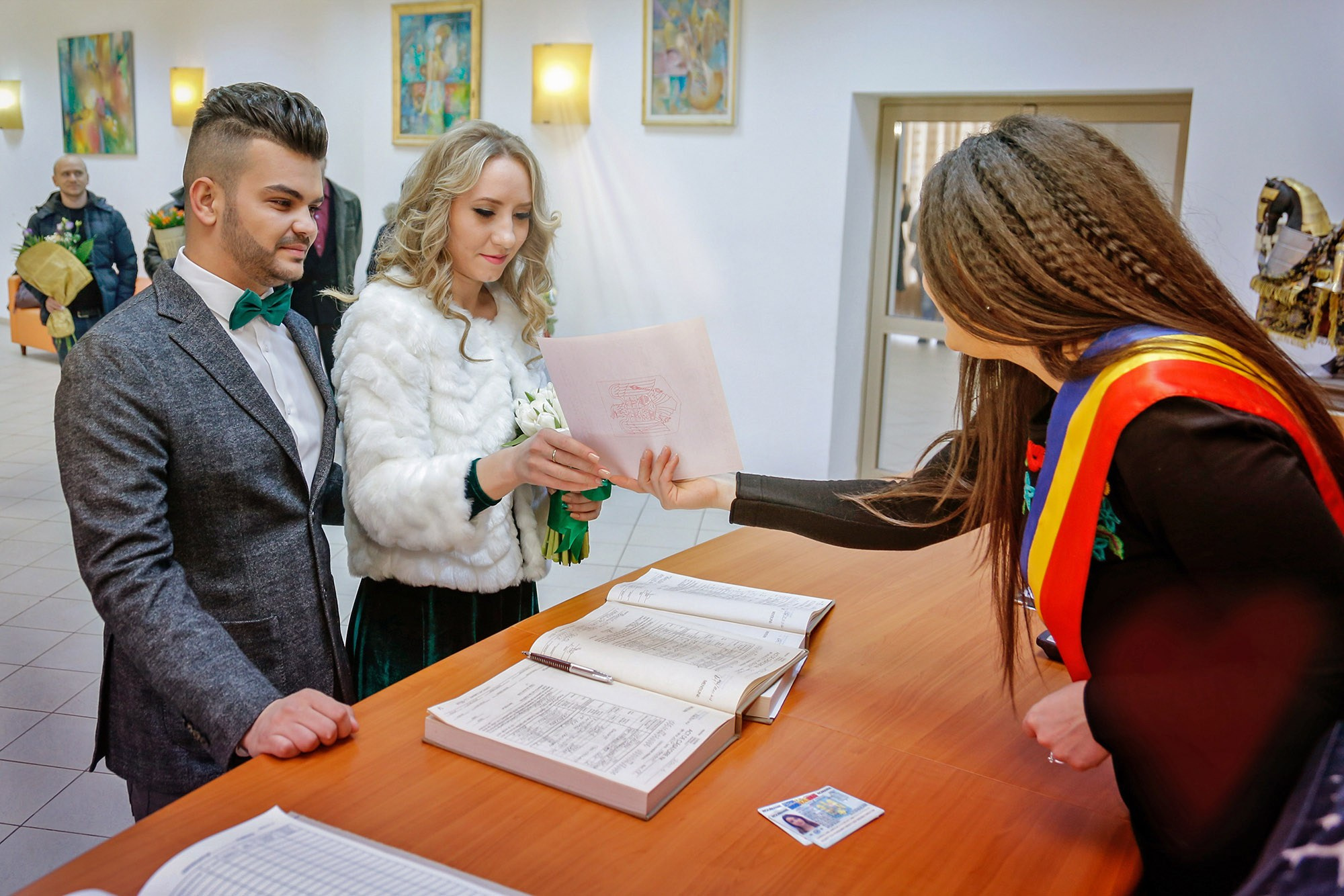 The marriage officiant presenting the official wedding documents to the newlyweds during the civil ceremony.