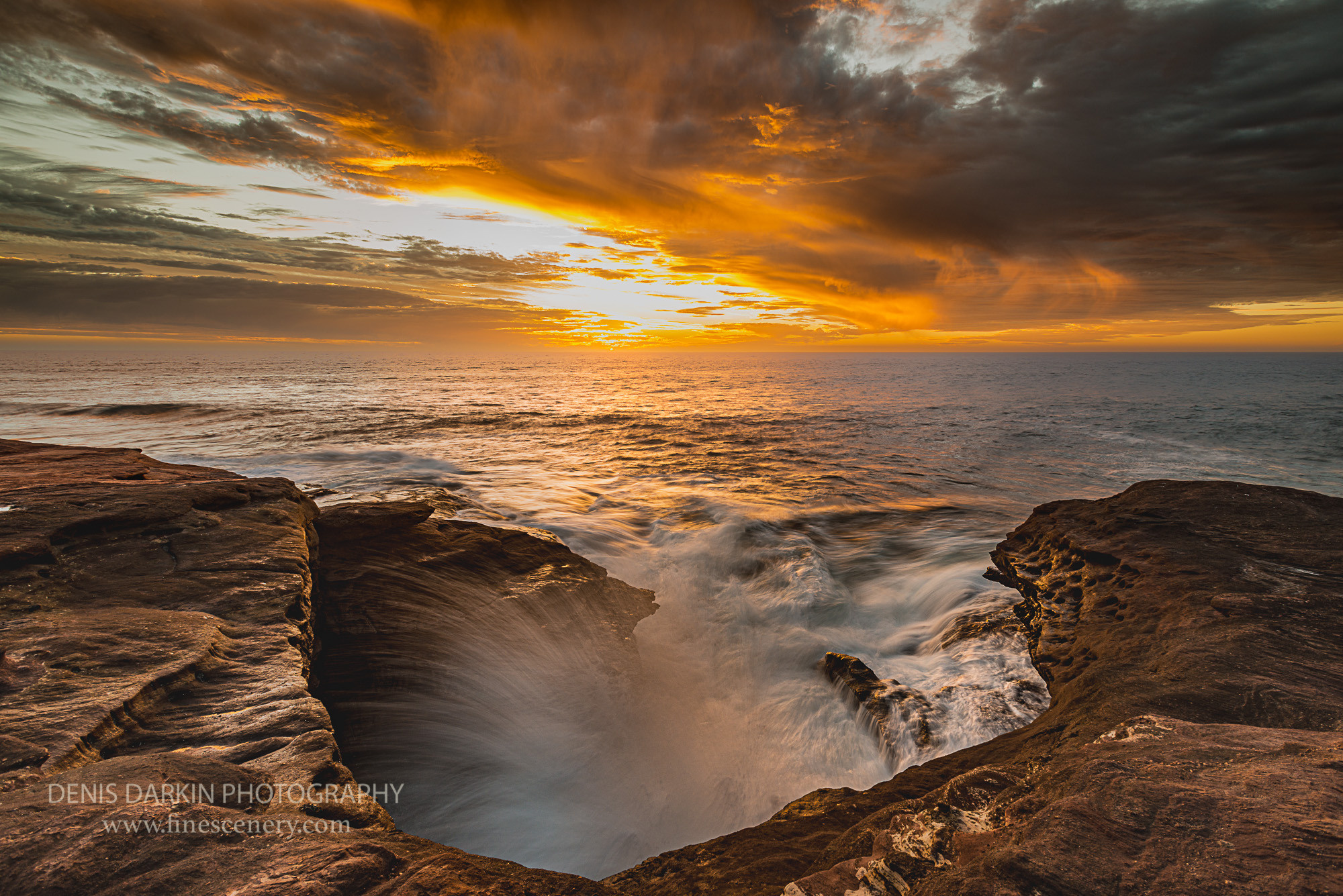 Spray from the ocean swell cover covers the red rocks of Western Australia coast. Blowhole, Indian ocean, Kalbarri, sunset, waves