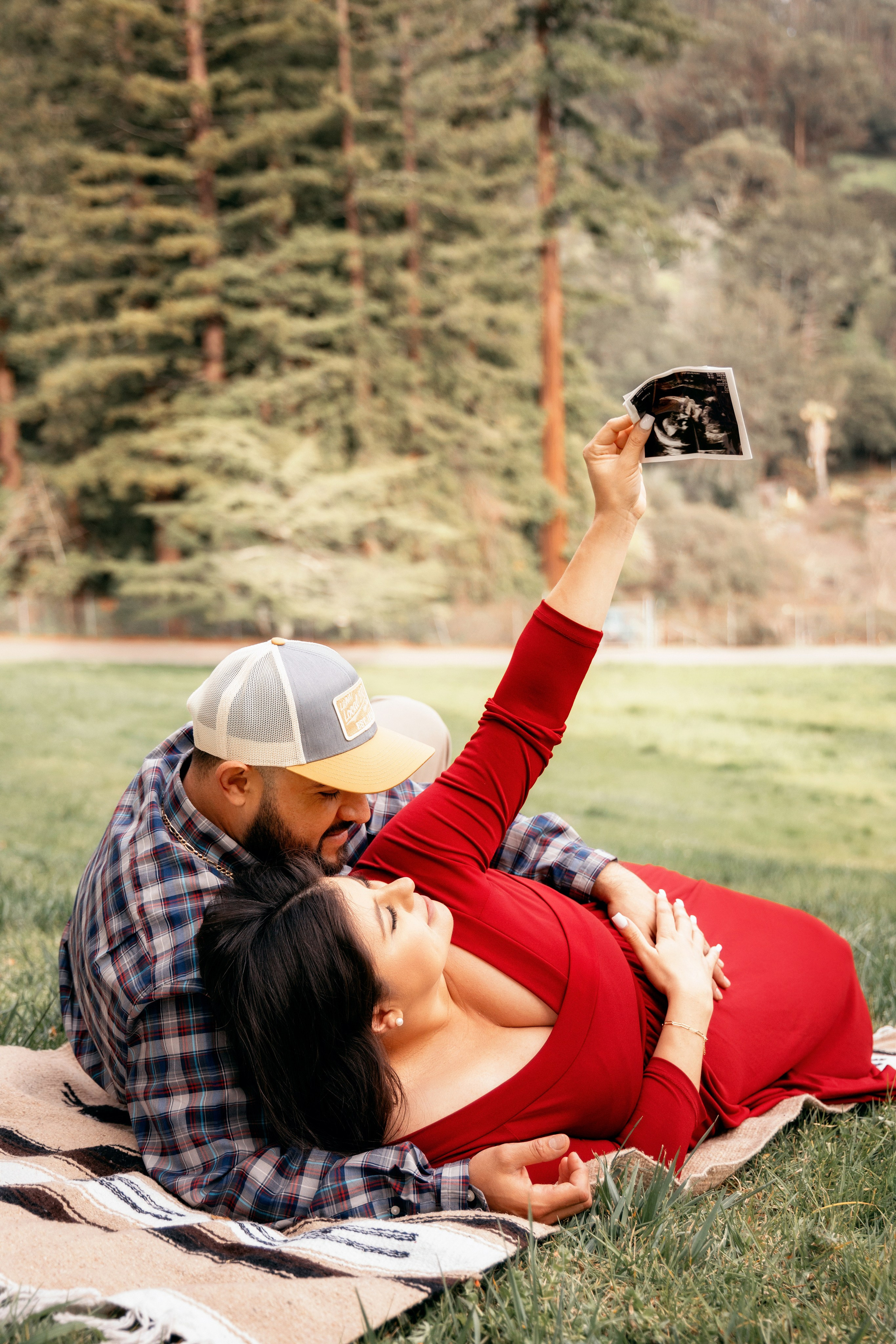 Pregnant couple embracing among the trees in the forest
