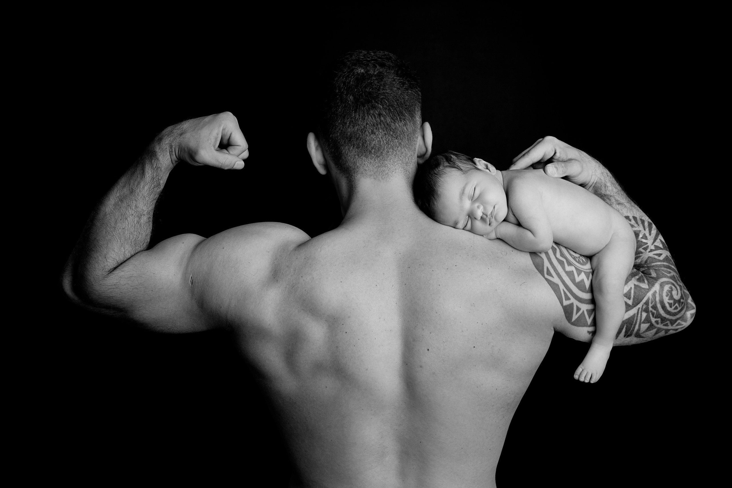 Pappa håller sin nyfödda bebis i famnen, ett fotografi från fototillfället fyllt av kärlek och stolthet.