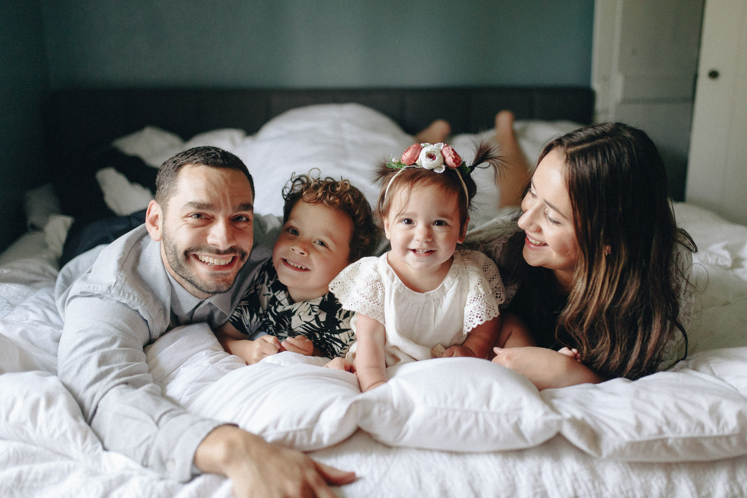 Family with kids laughing on bed, cozy indoor session