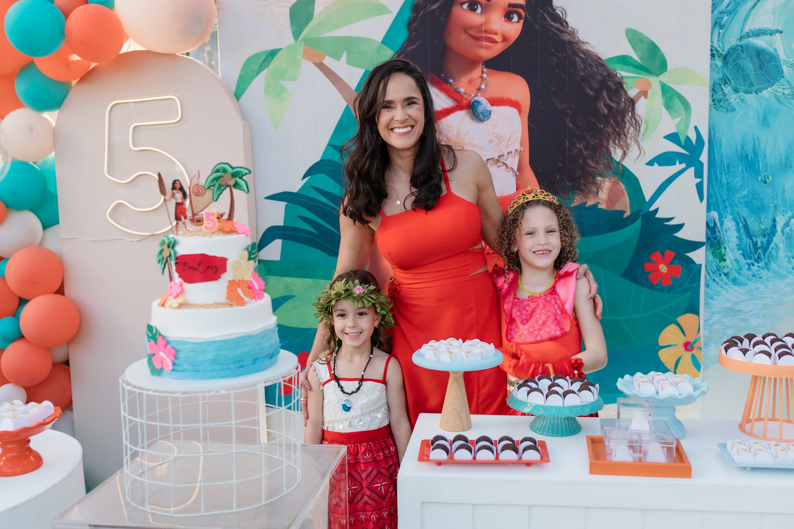Mãe e filhas posando na decoração da festa infantil