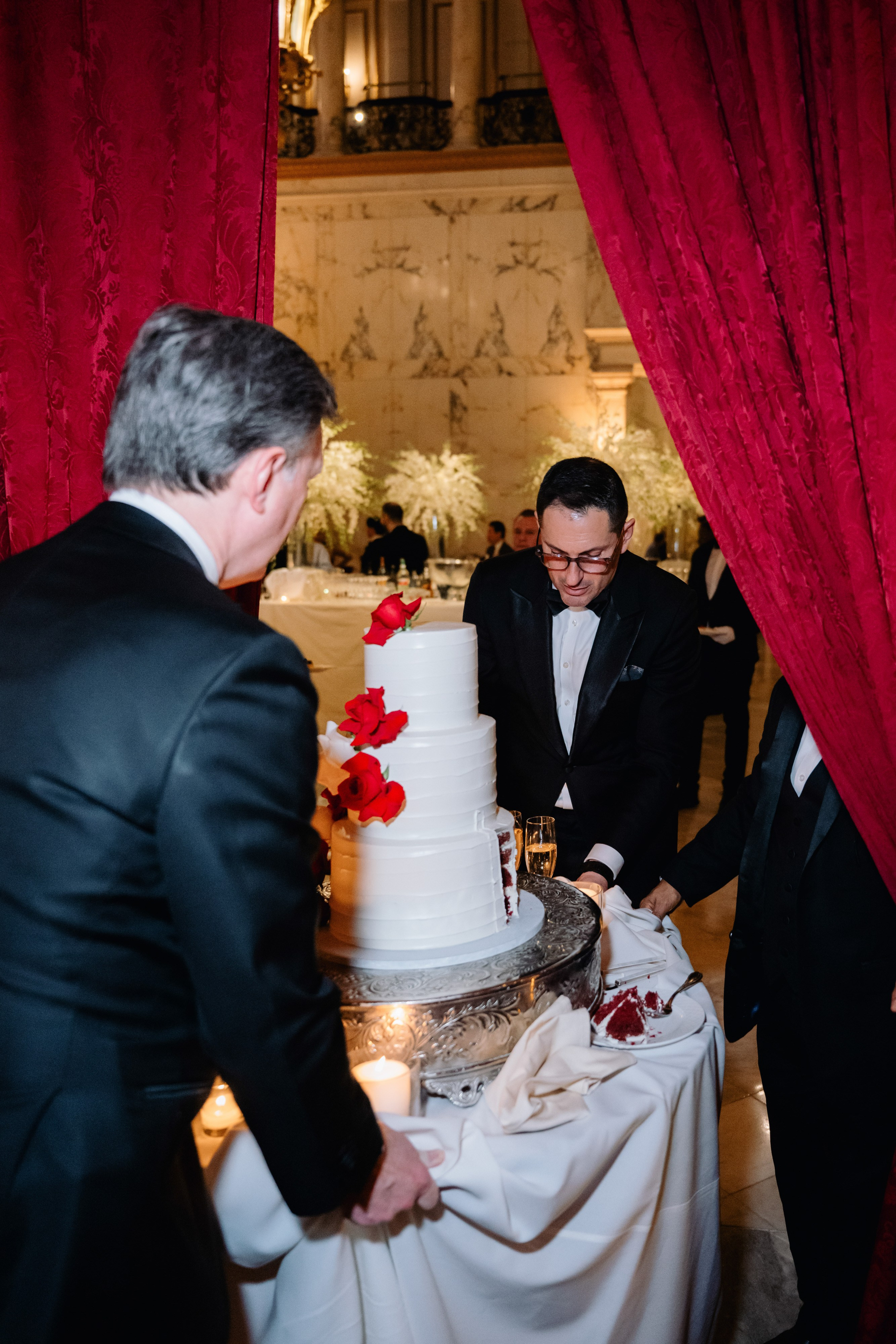 a man in a tuxed suit cutting a cake