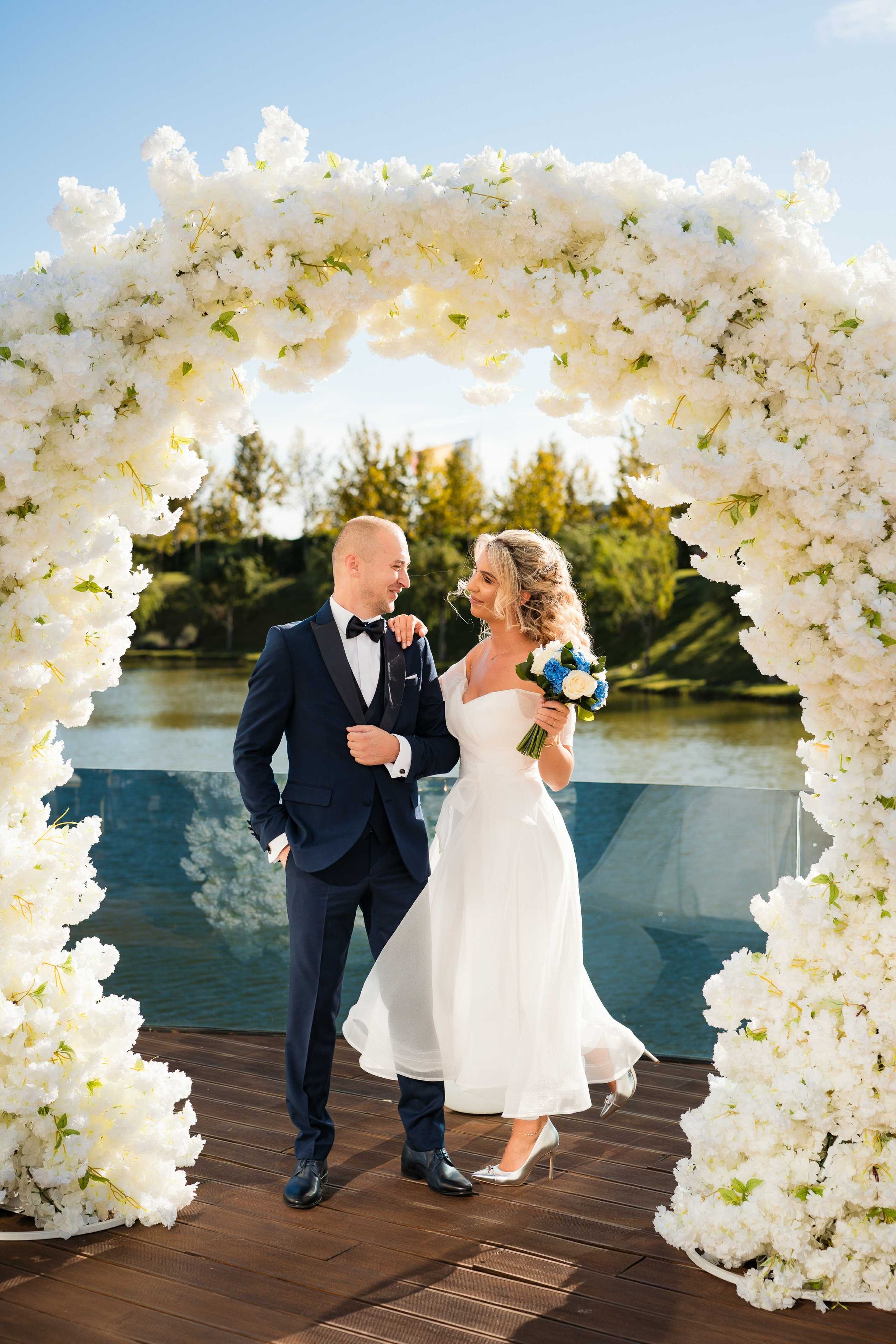 Mireasa râzând în brațele mirelui, într-un peisaj de poveste