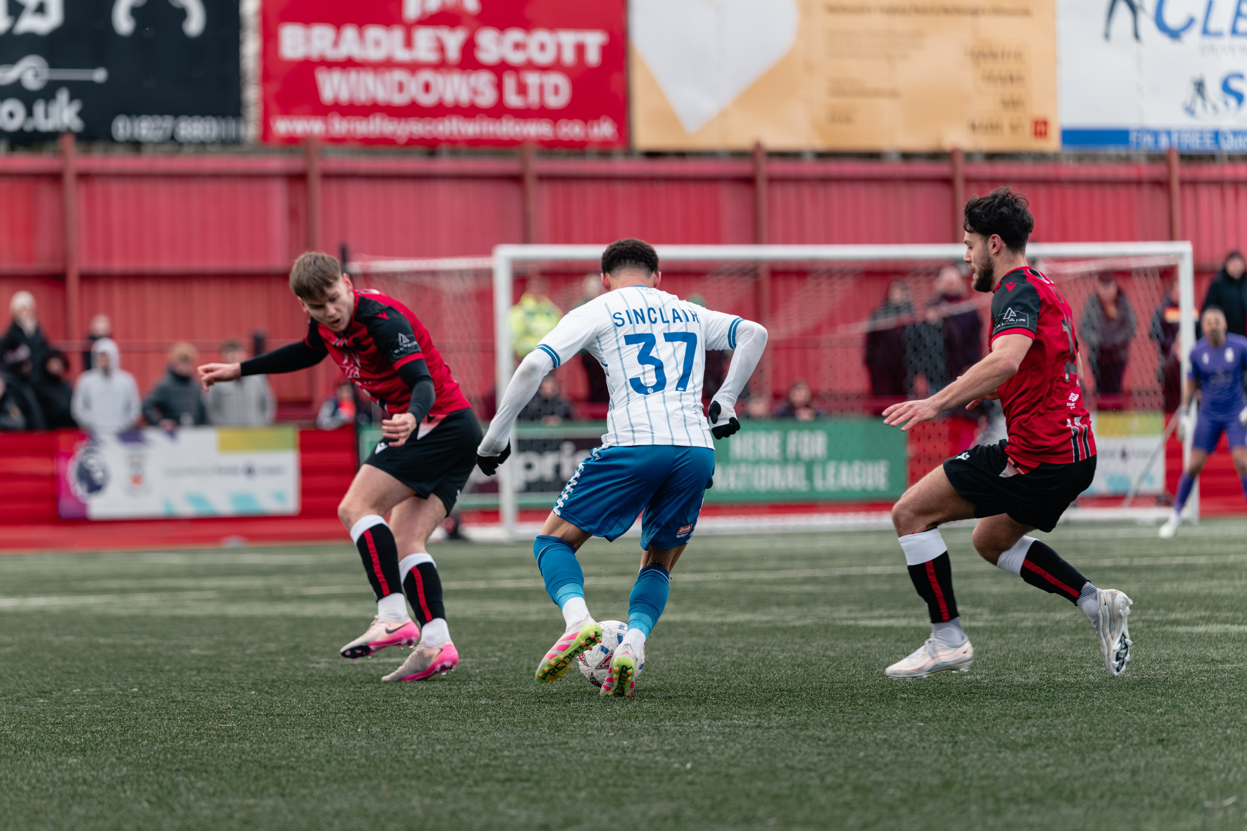 Hartlepool’s number 37 Sinclair challenged by two Tamworth players in midfield