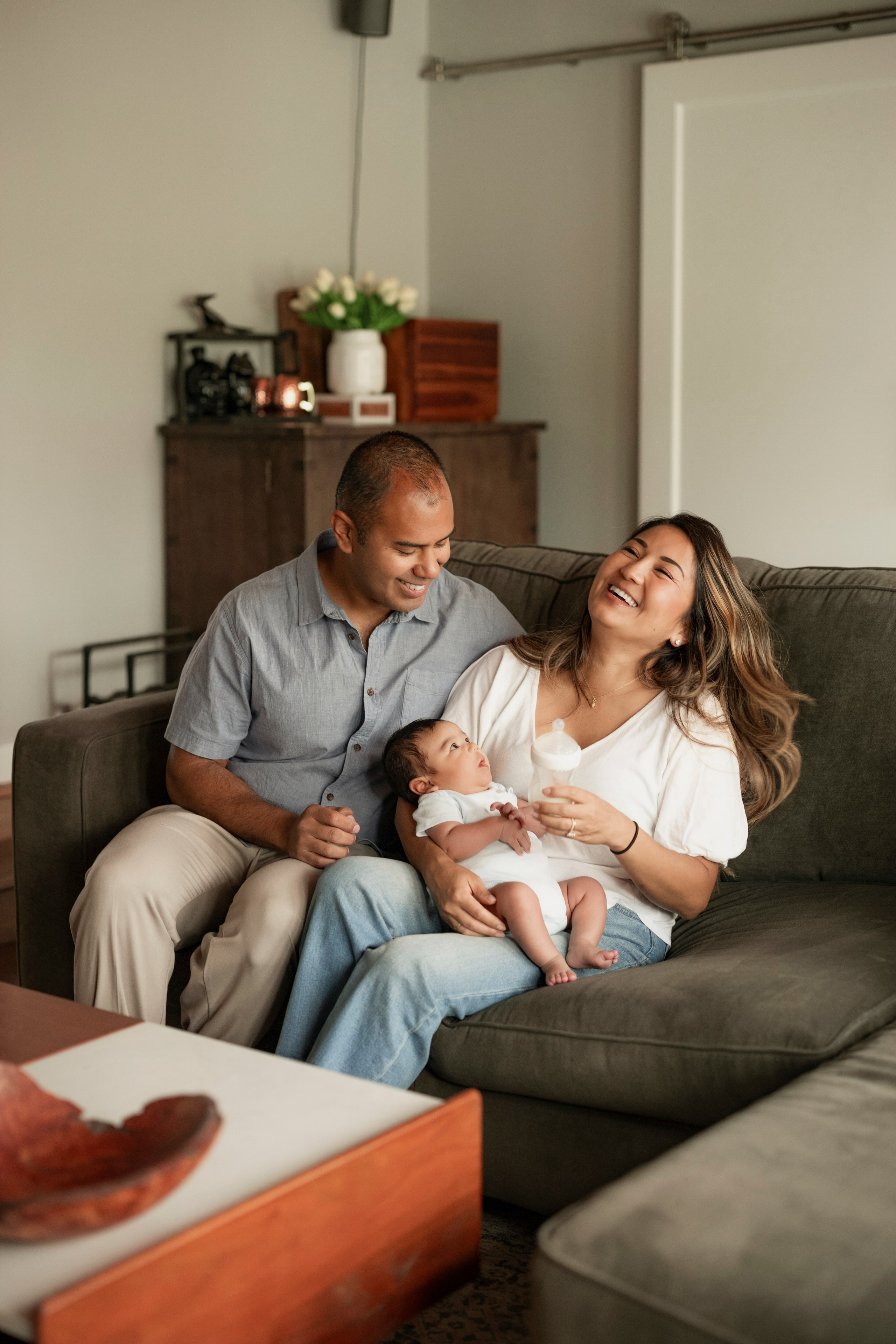Family cuddling on the couch with newborn during at-home photoshoot