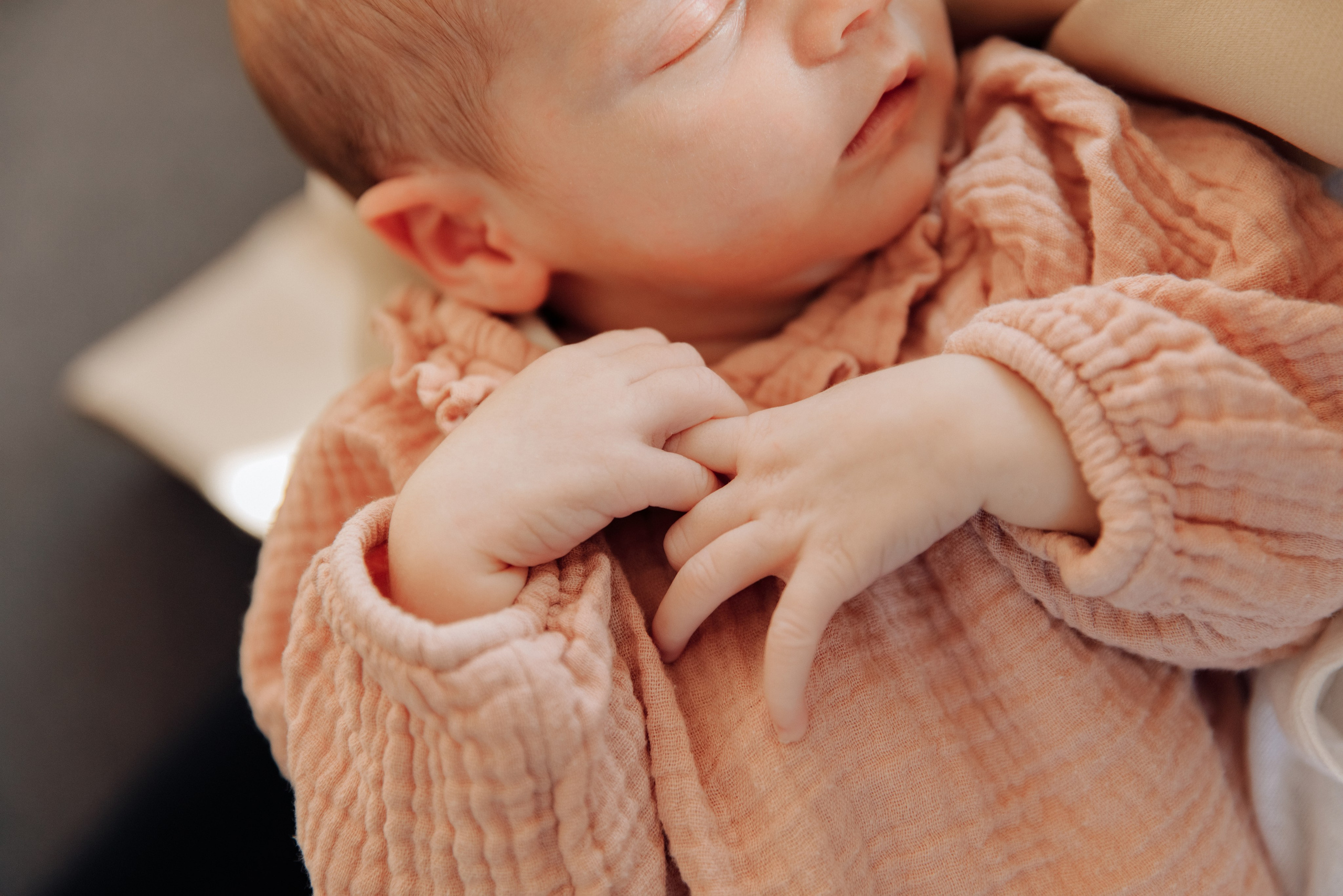 Neugeborenes hält sich mit seinen kleinen Händchen fest. Ein zarter und liebevoller Moment.