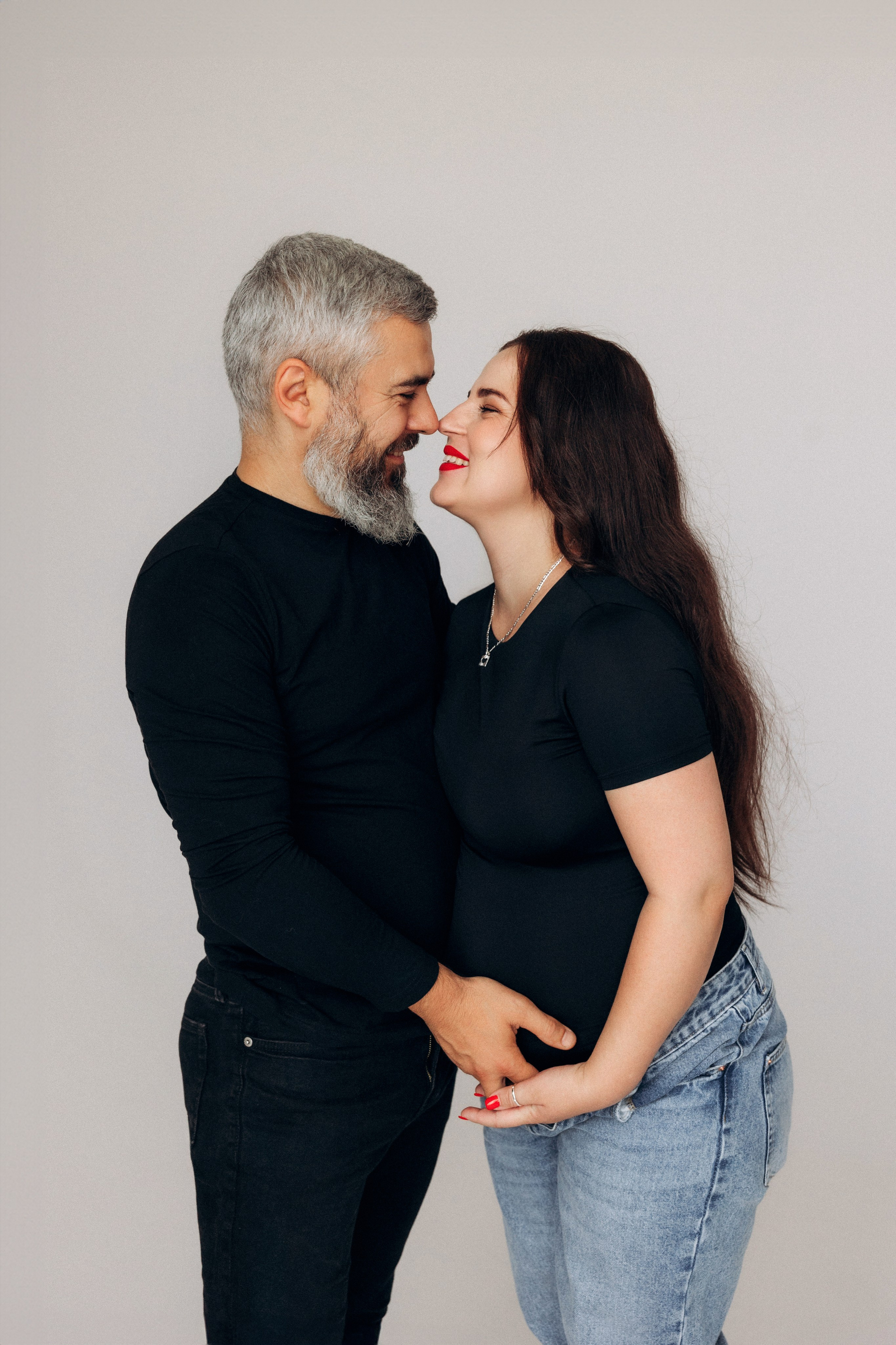 Bliskość i oczekiwanie – przyszły tata delikatnie dotyka brzucha partnerki, fotografia emocji.