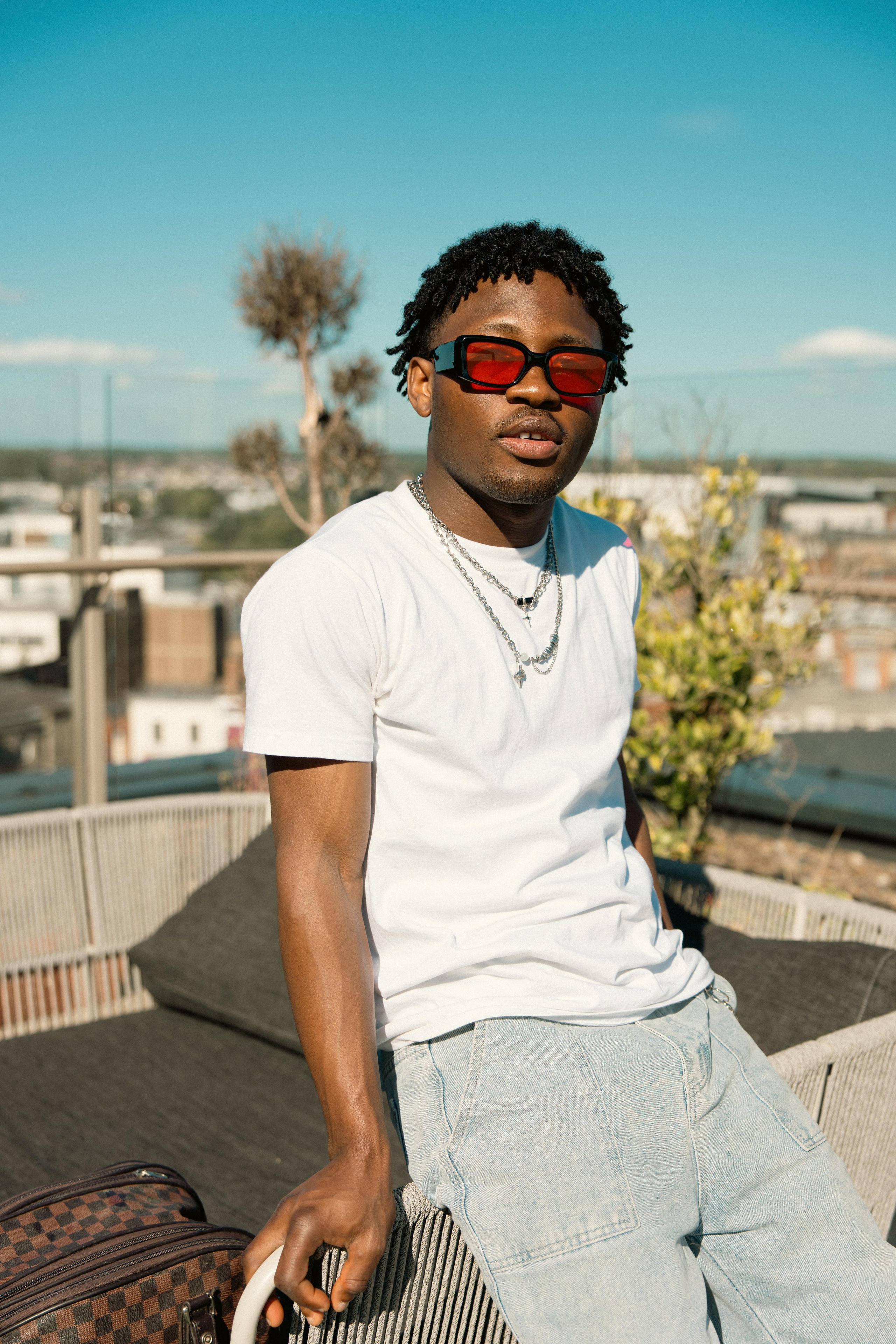 Rooftop fashion portrait of a male model wearing red sunglasses
