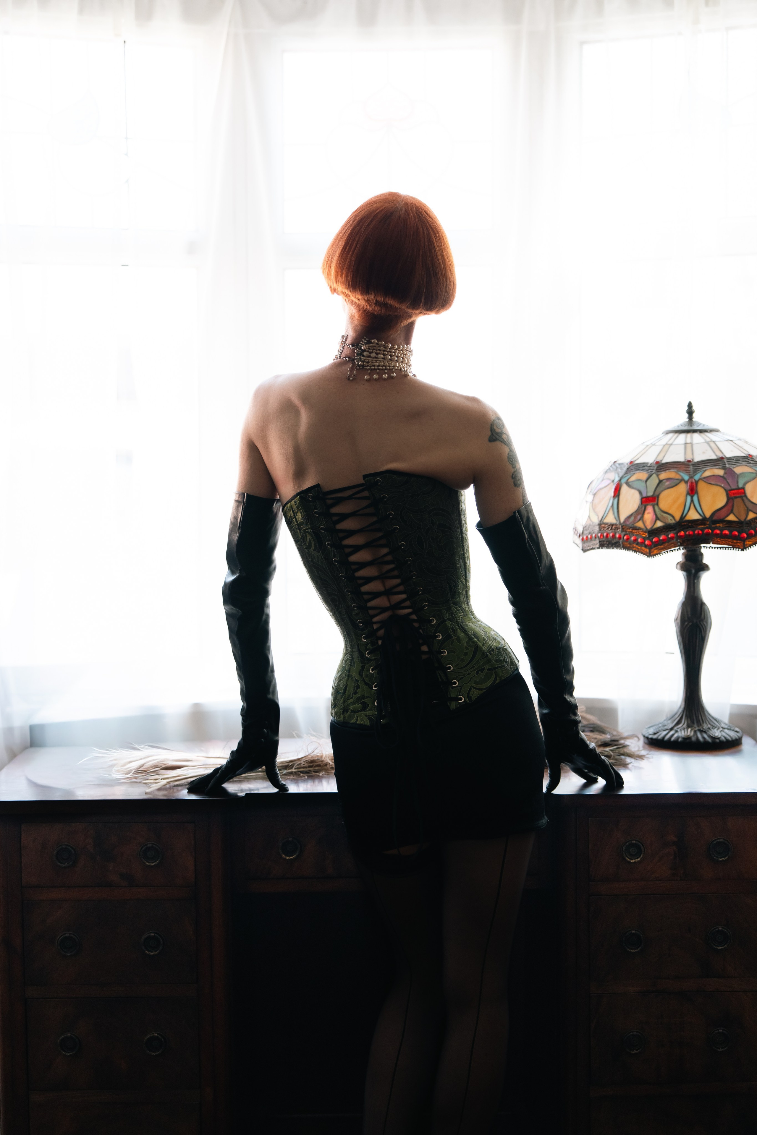 Creative backlit portrait of a woman in a corset and long gloves