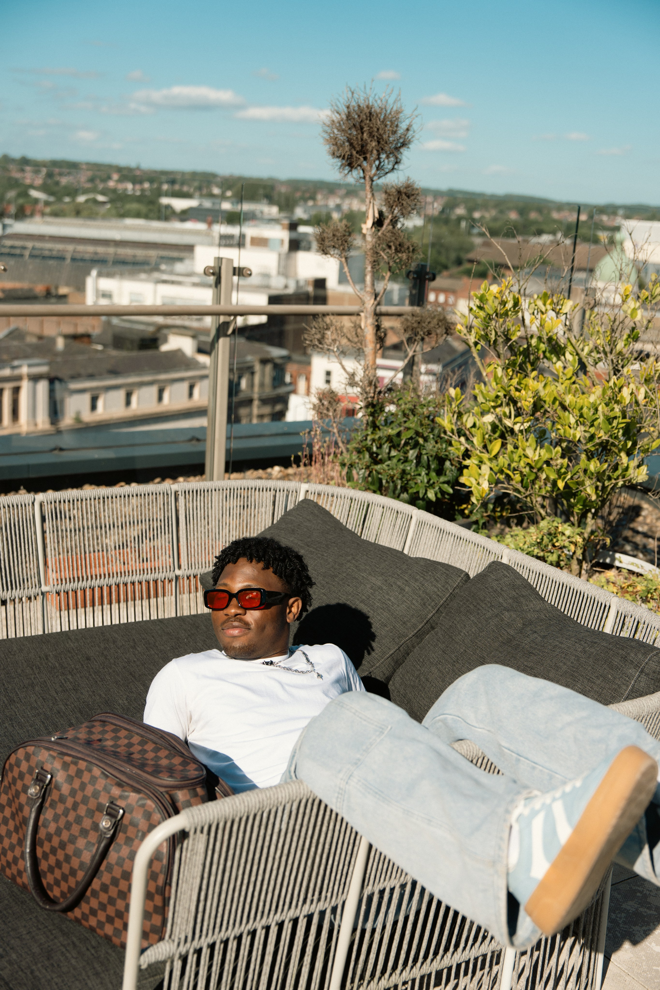 Male model relaxing on rooftop seating during an editorial fashion shoot
