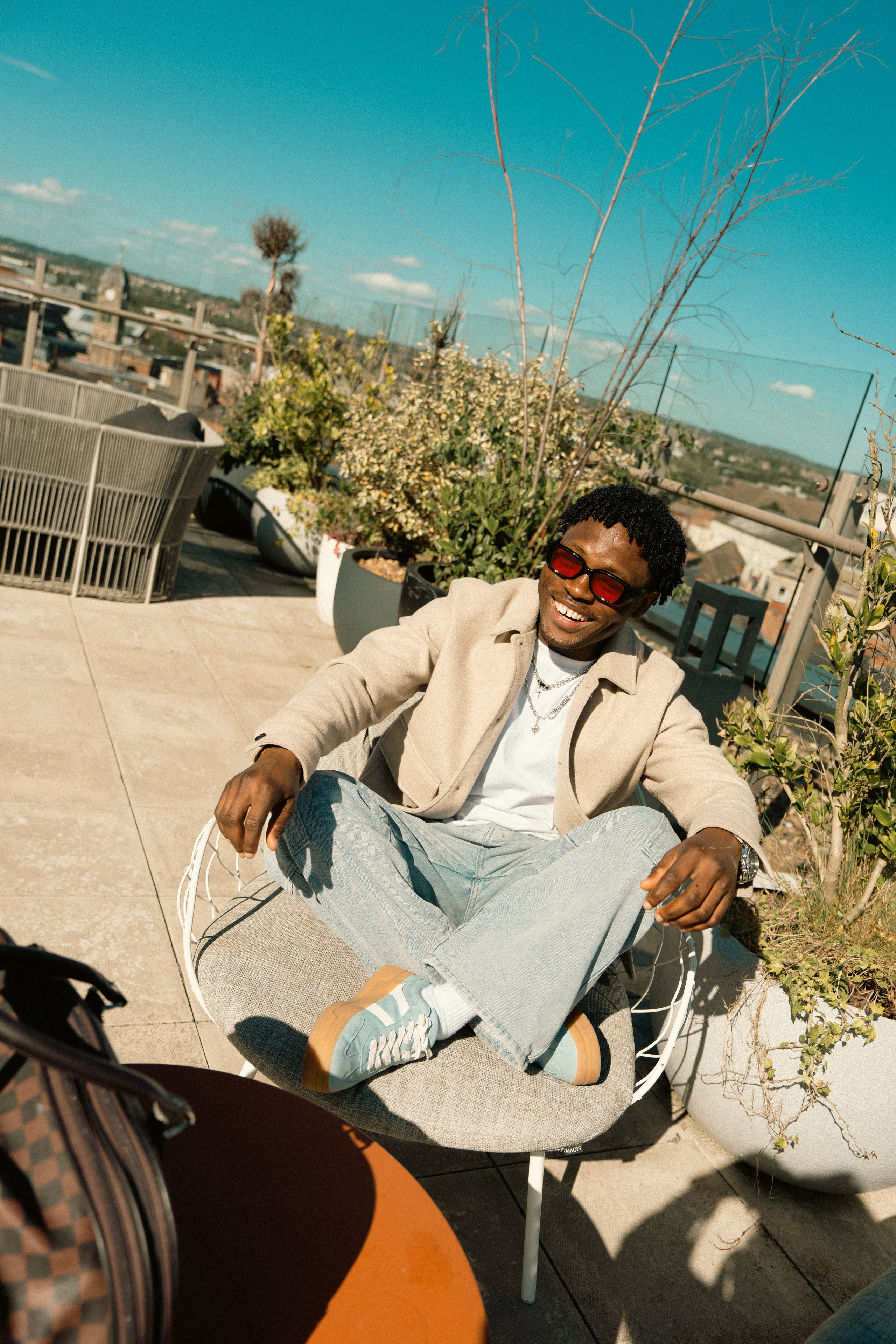 Male model in sunglasses relaxing on a rooftop, lifestyle fashion photography