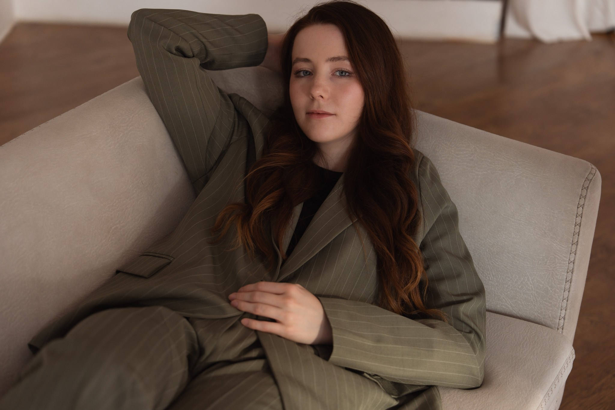 Female portrait in a pinstripe suit reclining on a sofa, Derby