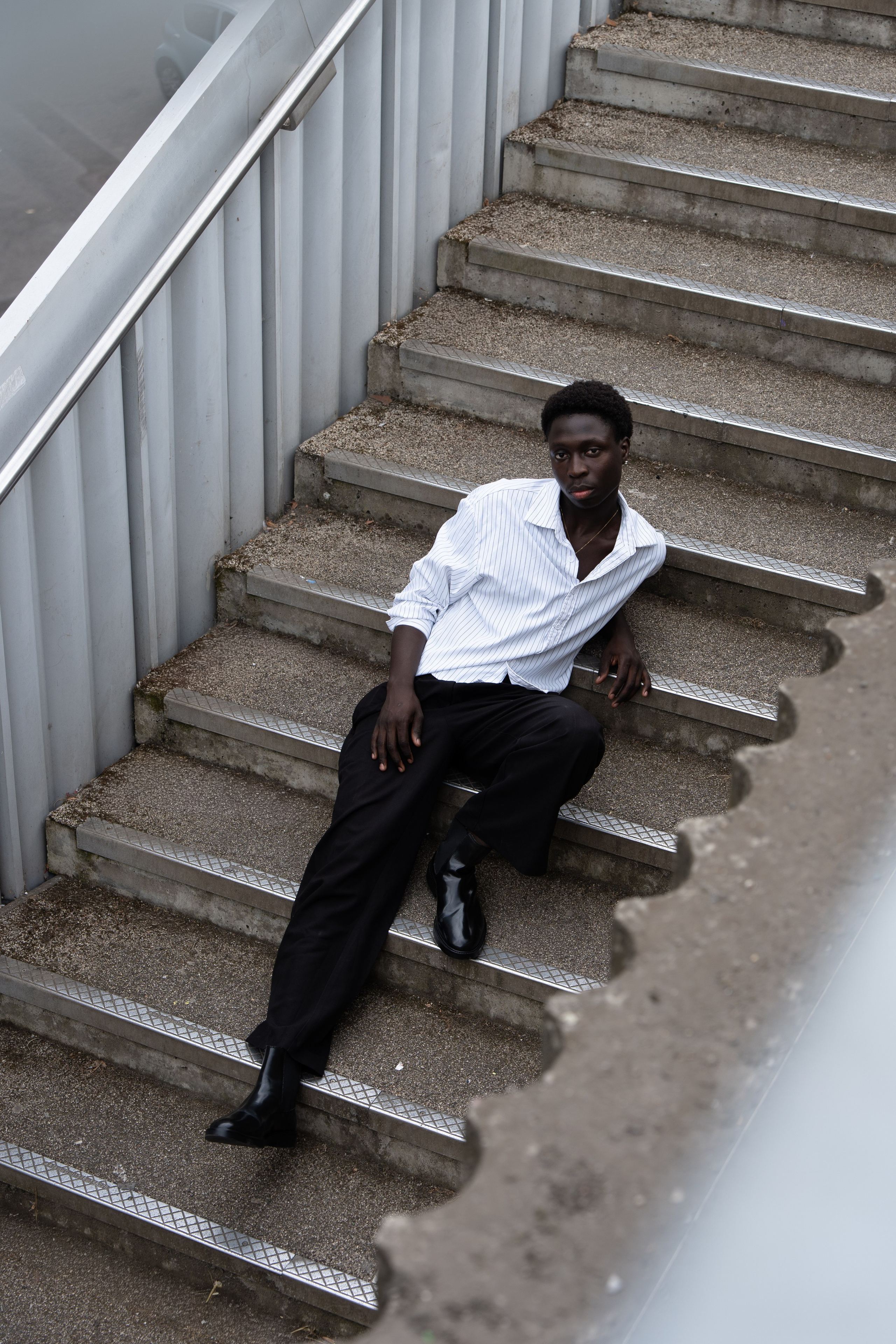 Male model seated on an urban staircase, editorial fashion photography