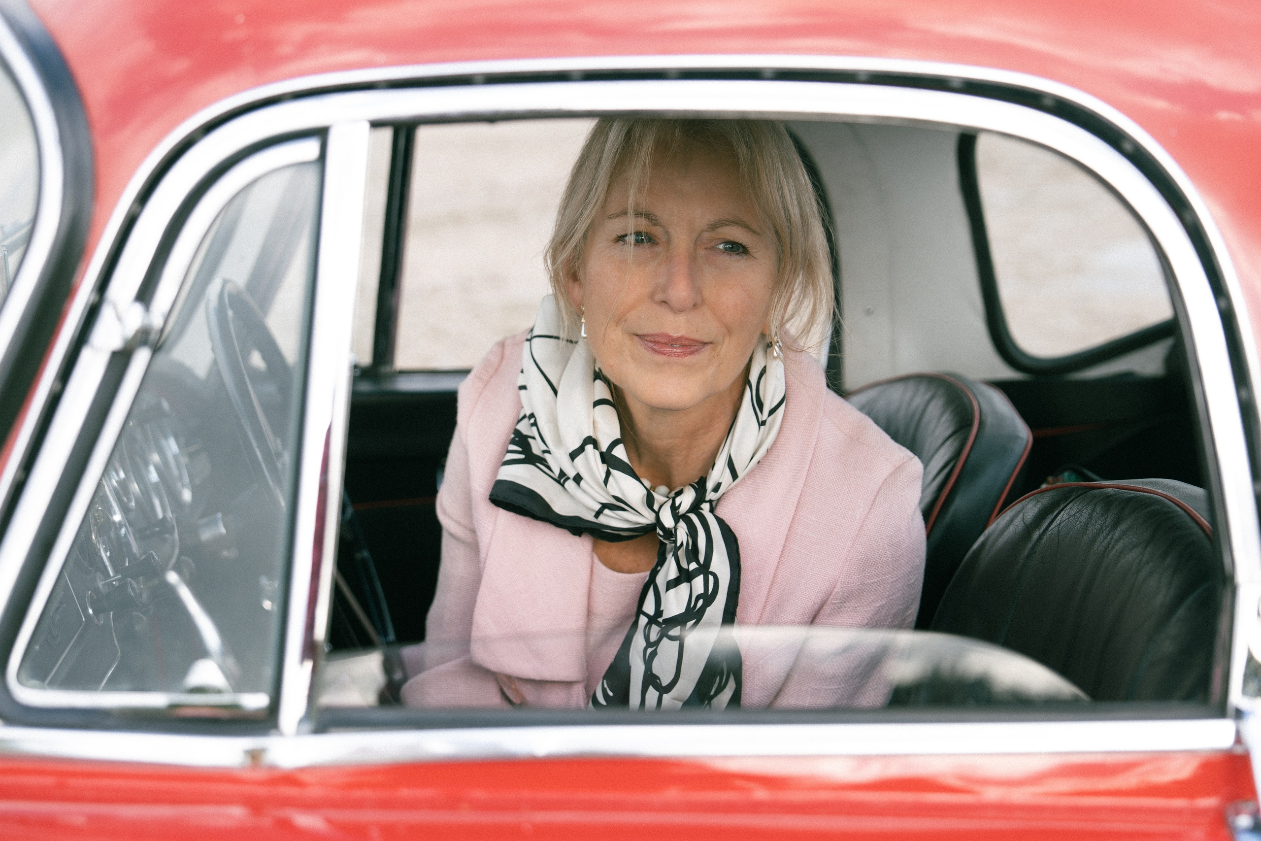Female portrait framed through the window of a classic red sports car