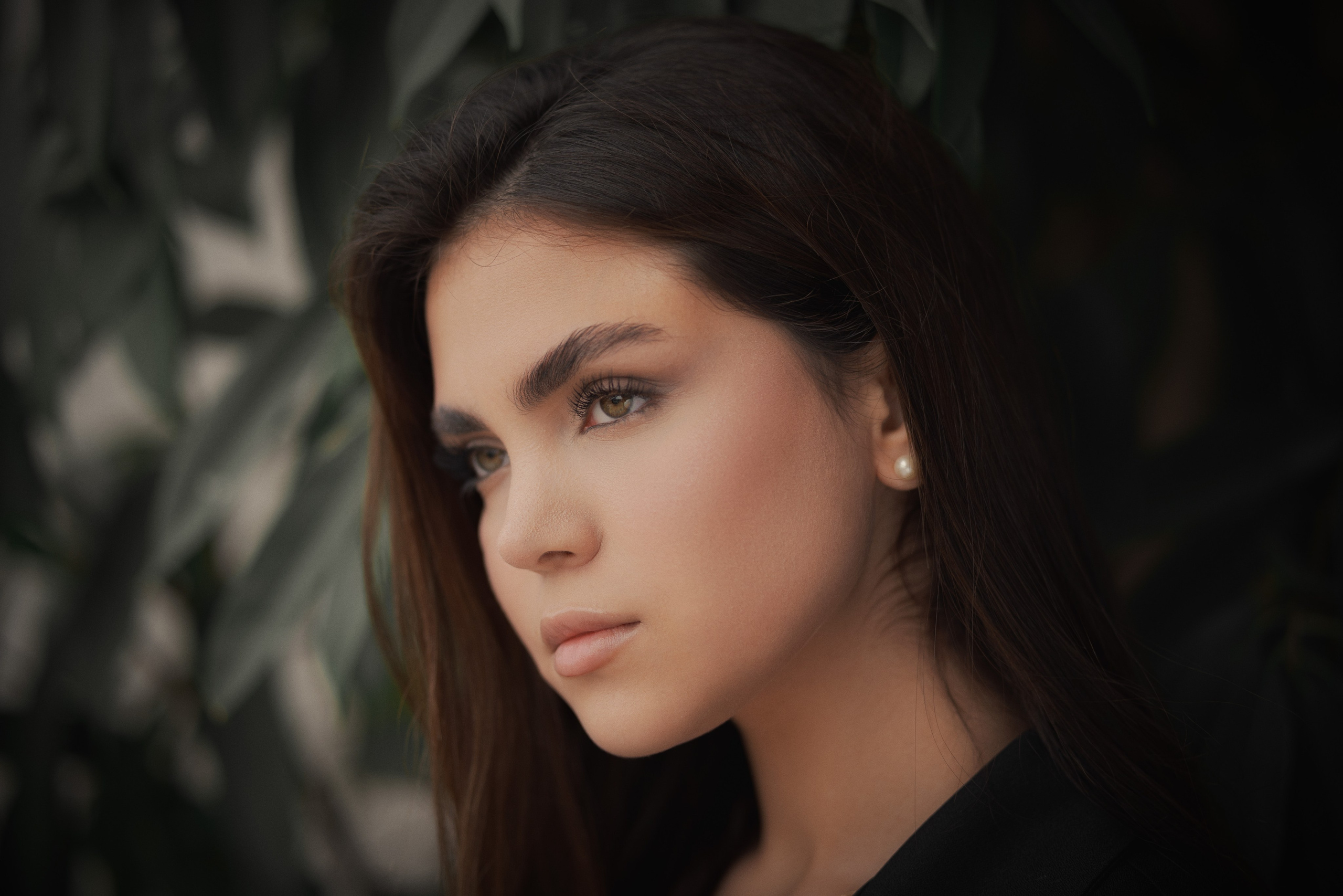 Female portrait photography by Mehran Hadad with soft natural light, green foliage background, and cinematic color grading.