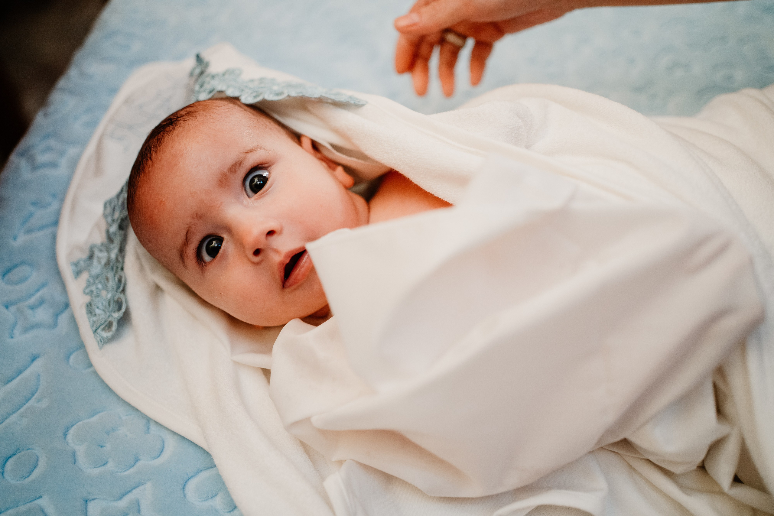 Instantaneu plin de tandrețe dintre părinți și bebeluș în ziua botezului, realizat în Bucuresti. Fotografie profesională de botez, capturând emoțiile autentice ale familiei într-un decor luminos și cald