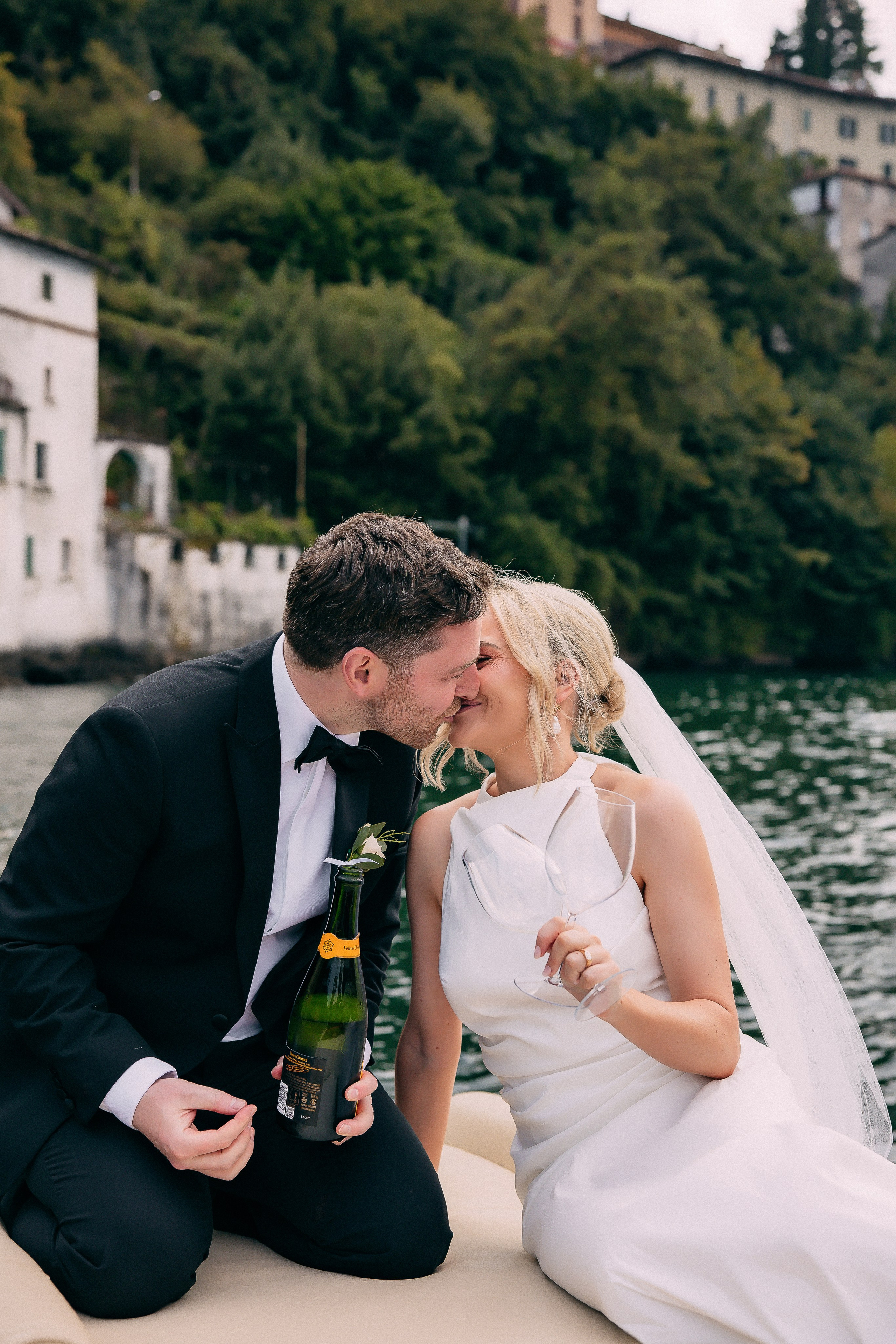 Groom pouring champagne for the bride on the boat at Villa Lario, Lake Como, Italy