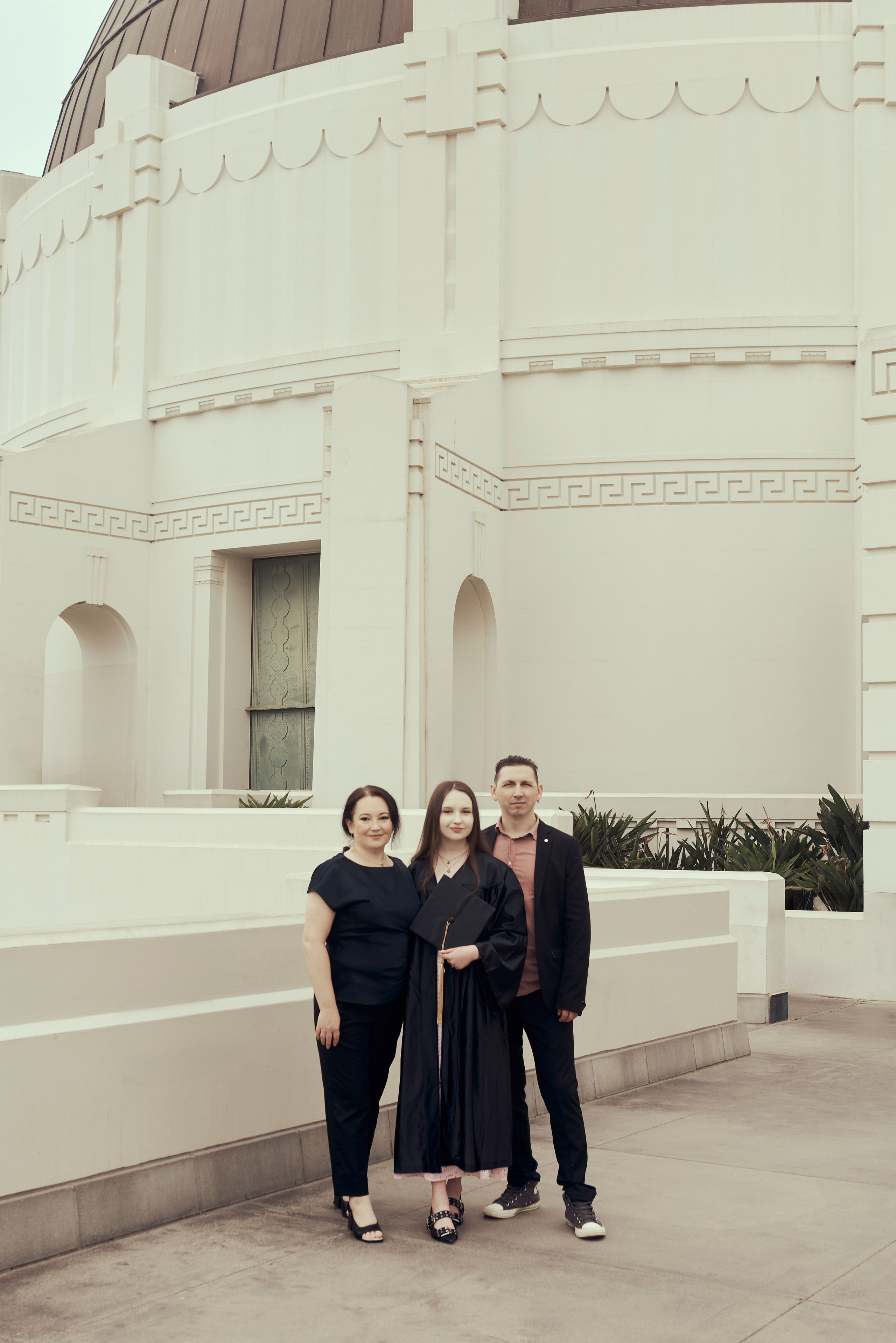 Graduate and family posing with the iconic Los Angeles palm trees