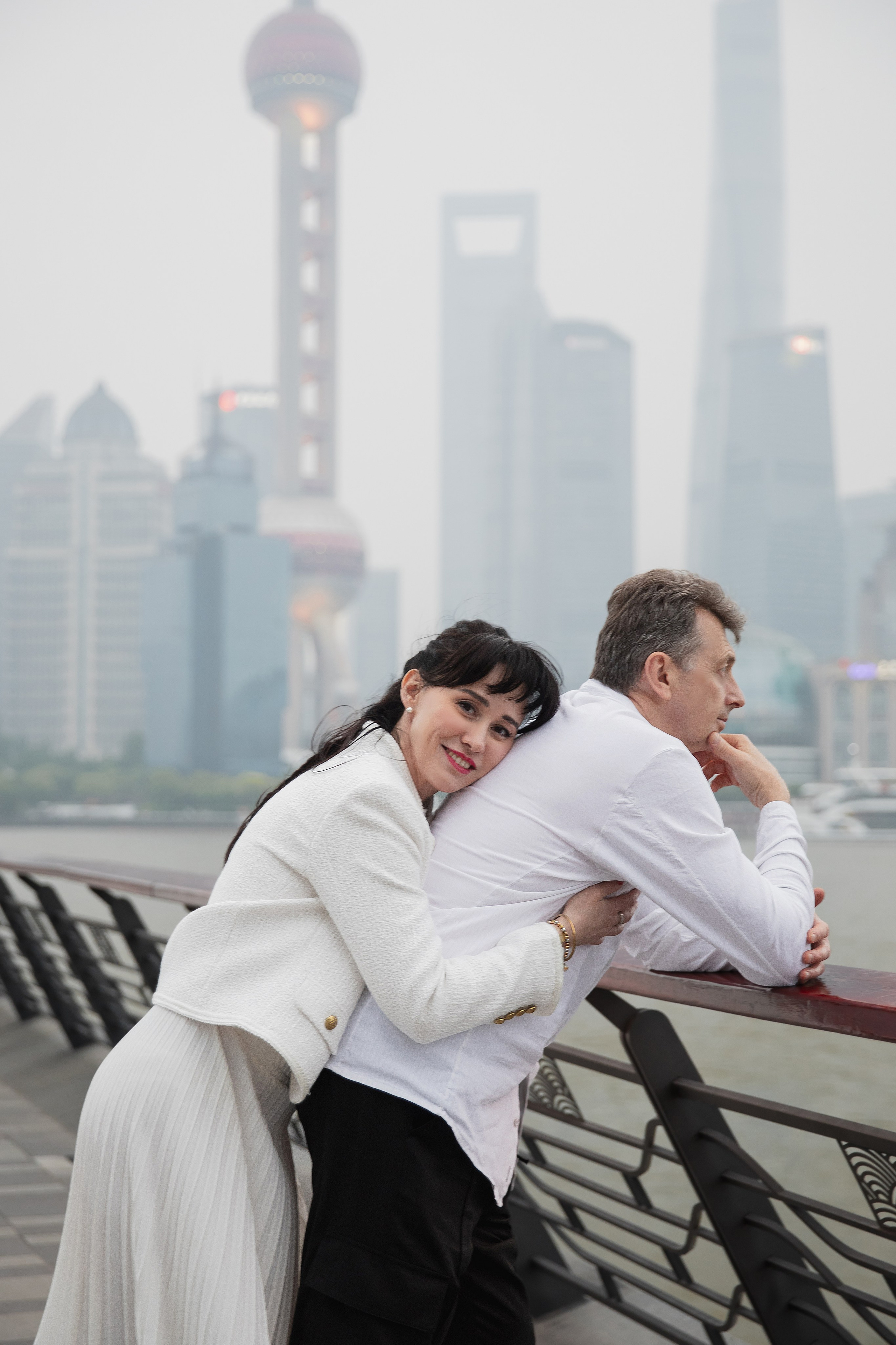 Пара обнимается на фоне ночного Шанхая с огнями небоскребов