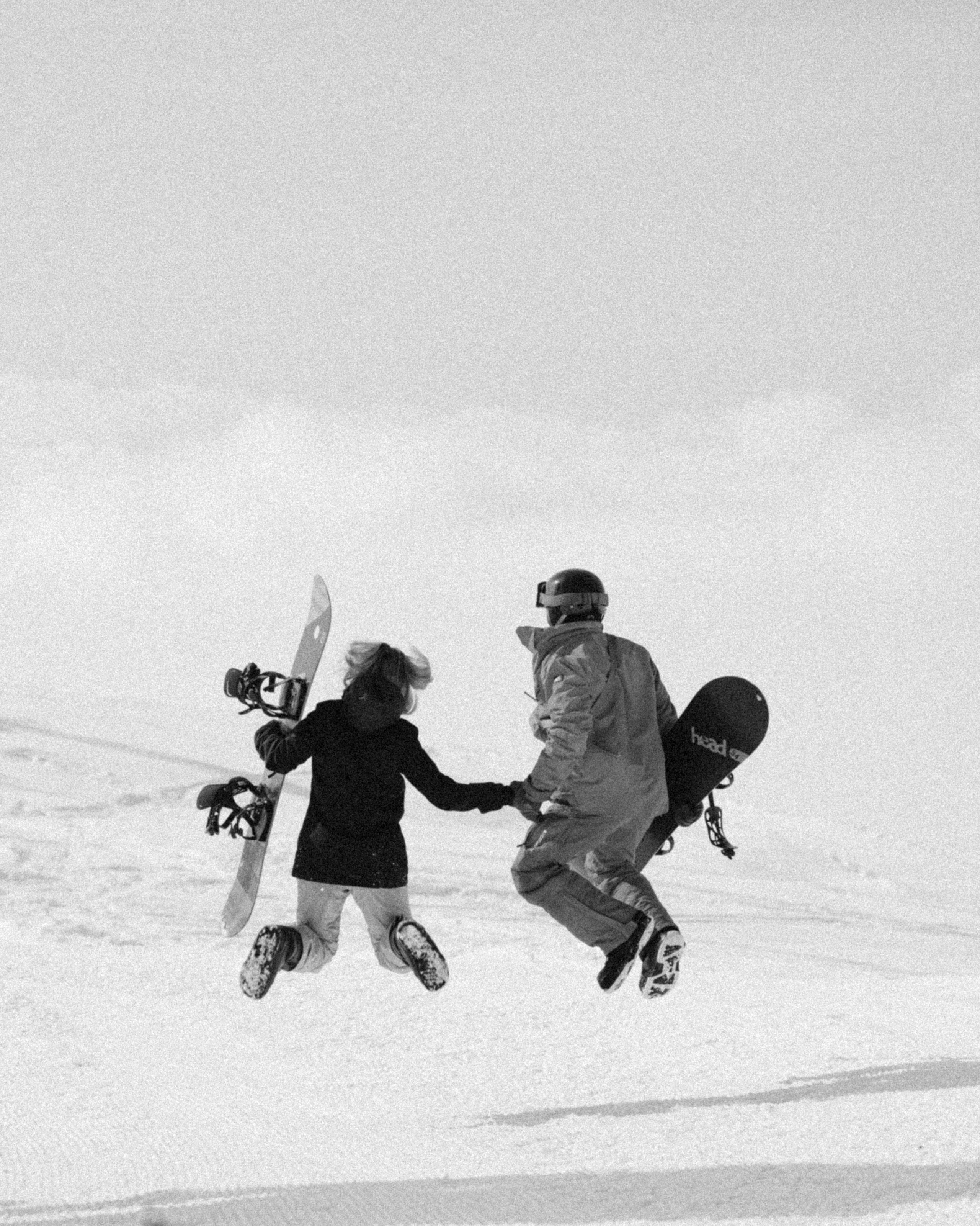 snowboarders couple jumping during during surprise snowboard proposal at Gudauri ski resort