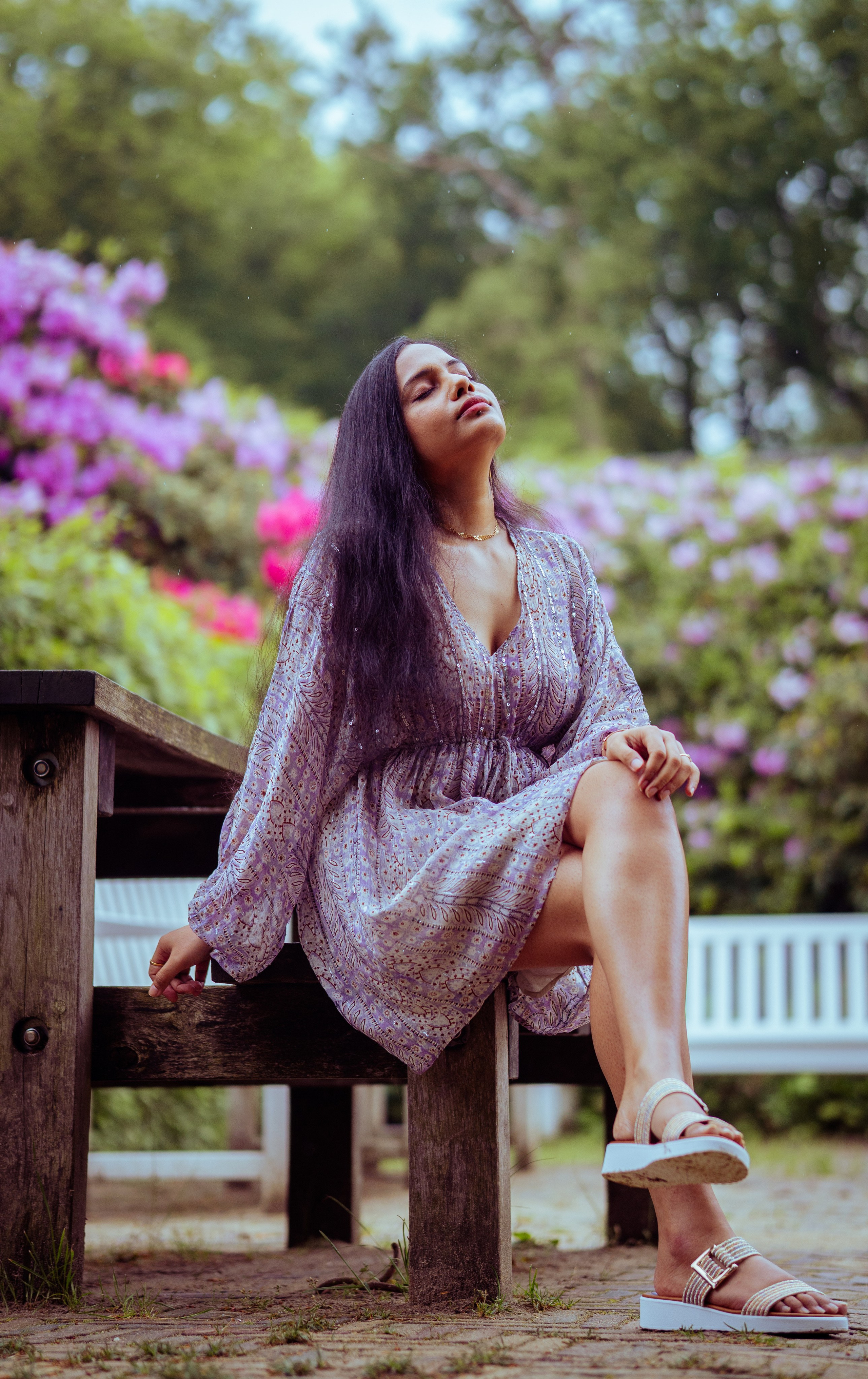 woman sitting on a white bench with flowers as background