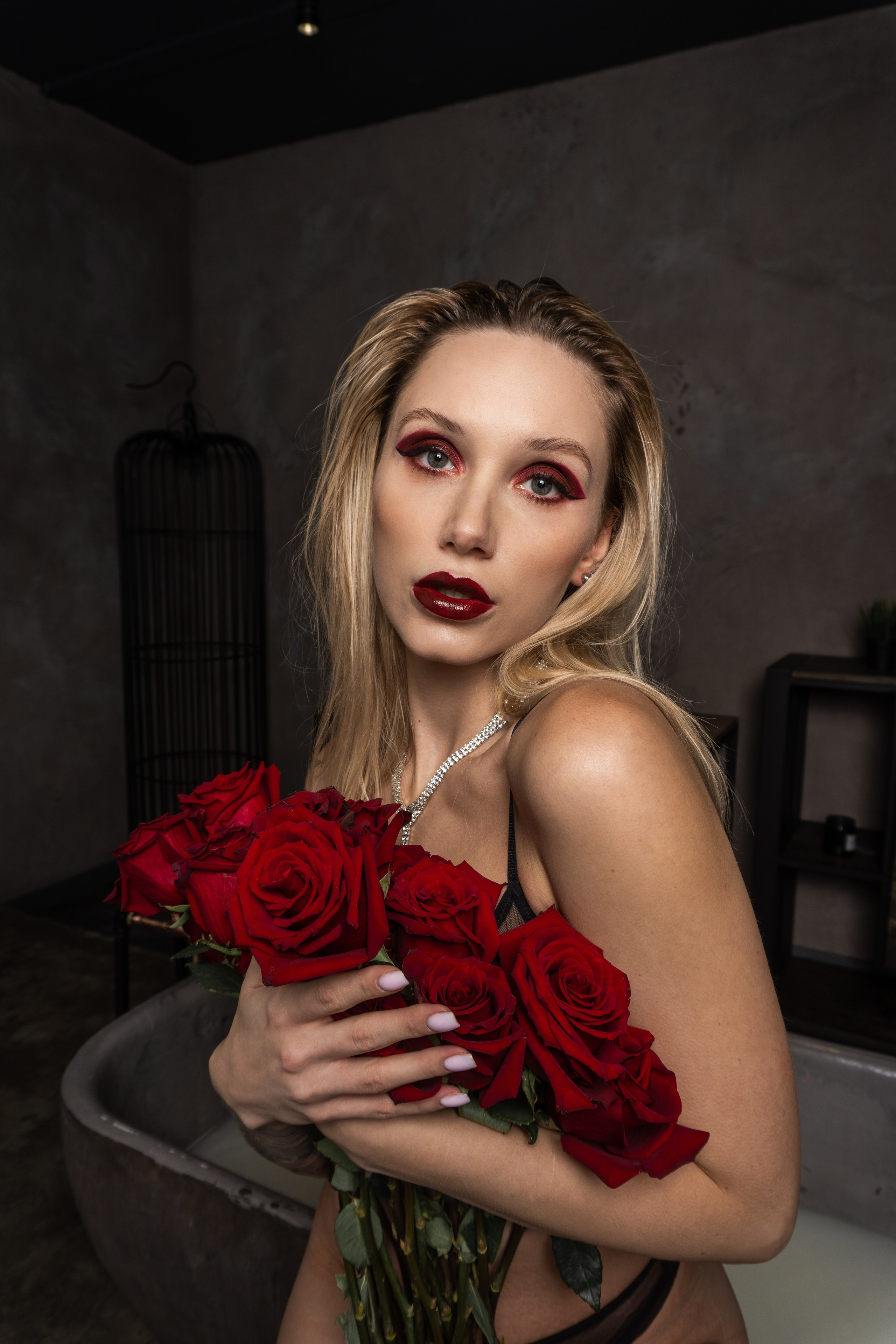 Blonde woman holding a bouquet while wearing black lingerie.