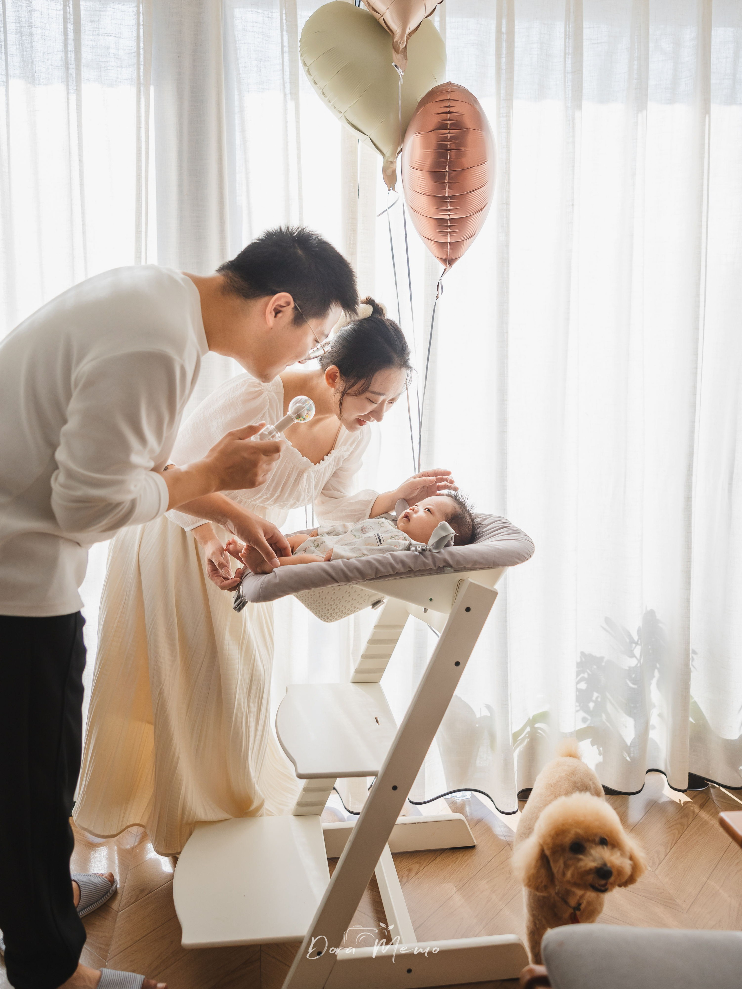 Parents standing by the window holding their newborn baby, captured in soft natural light during a Shanghai family photography session.