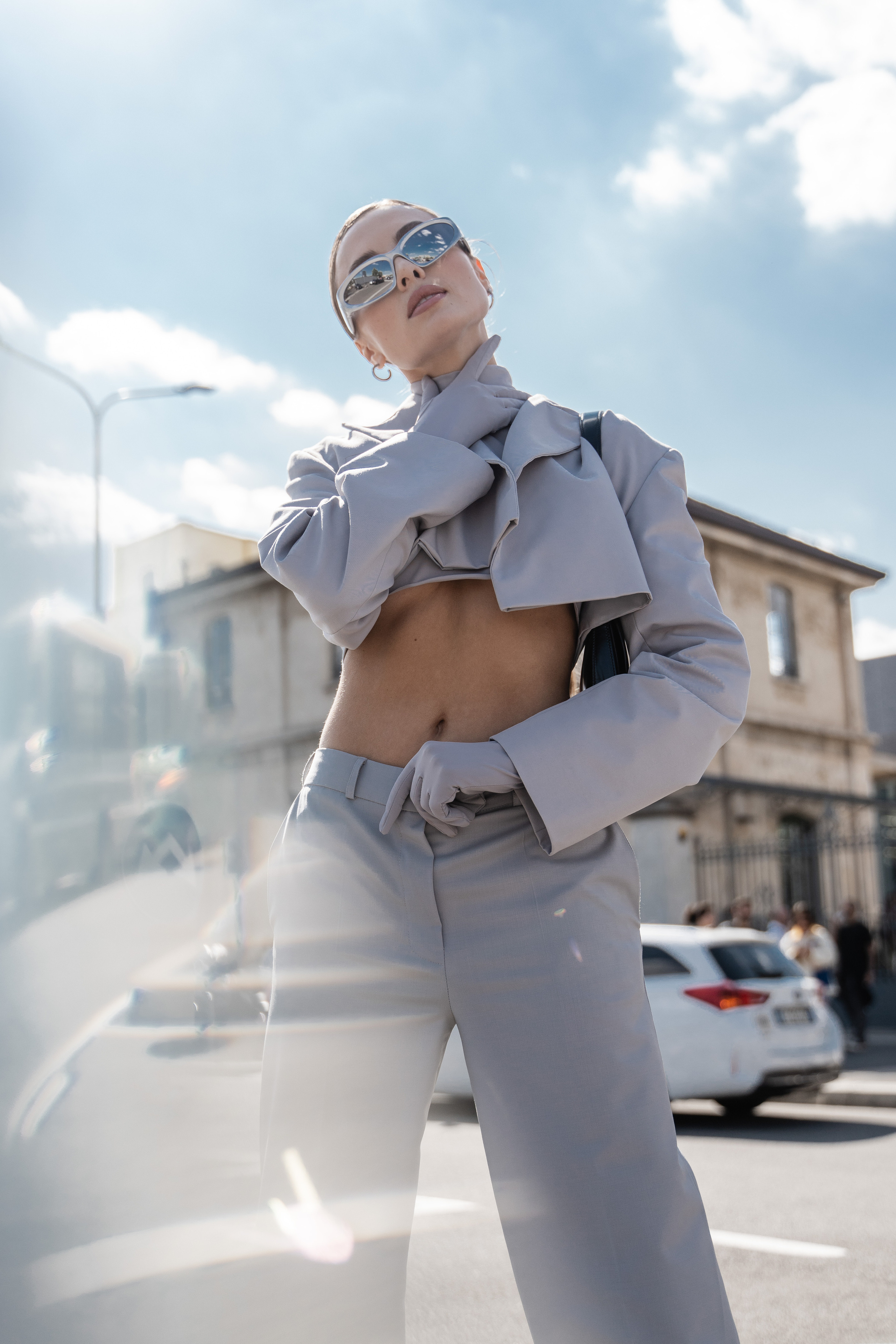 Street style fashion photography in Milan – stylish woman in a futuristic light blue outfit with sunglasses during Milan Fashion Week