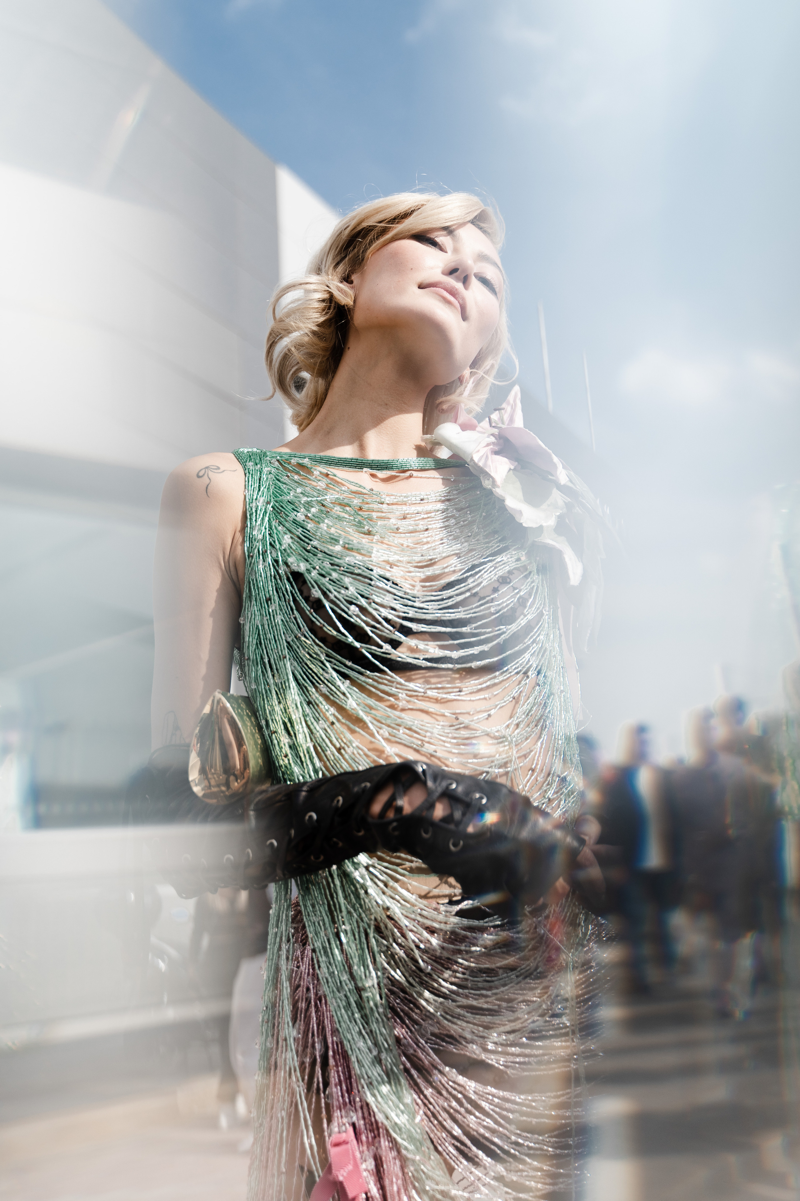 Milan Fashion Week fashion editorial – a model in a shimmering green fringe dress under natural light