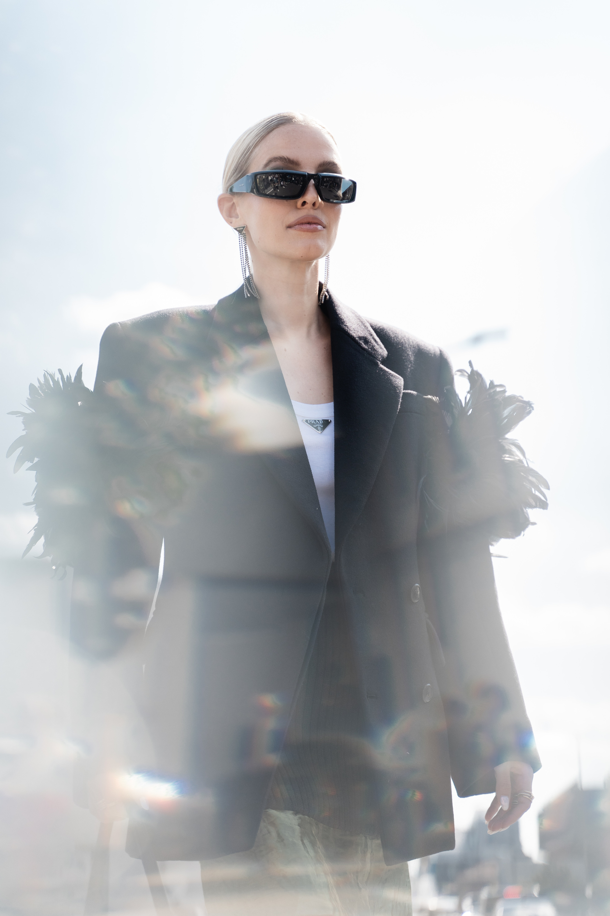 Fashionable woman in a structured black coat with a Prada handbag captured at Milan Fashion Week