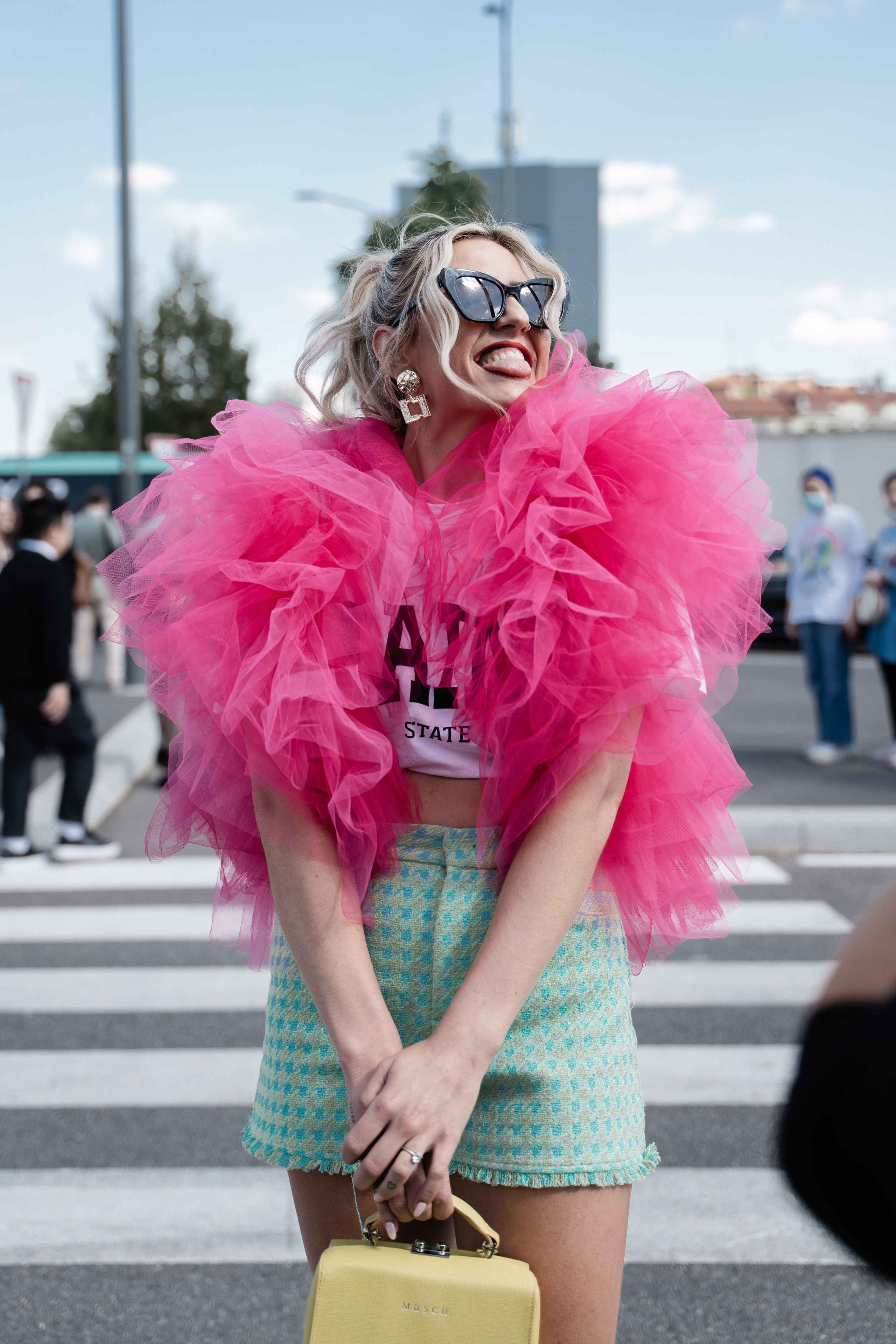 Cheerful woman in a pink ruffled top and pastel shorts, striking a playful pose during Milan Fashion Week