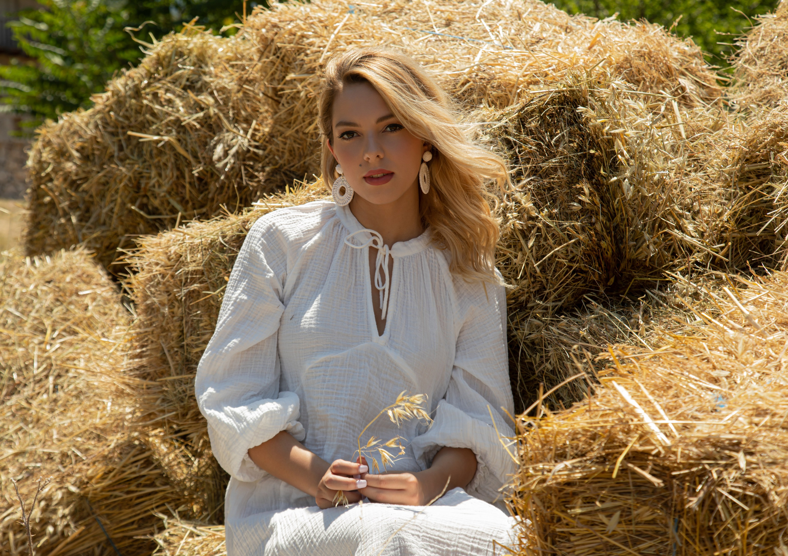 Portrait of a woman wearing a white bohemian muslin dress on a sunny farm
