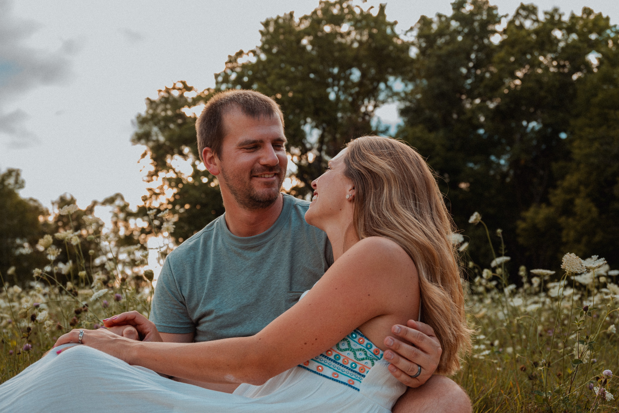 Joyful family laughing together during an autumn photoshoot in Wisconsin, with vibrant fall colors in the background. 