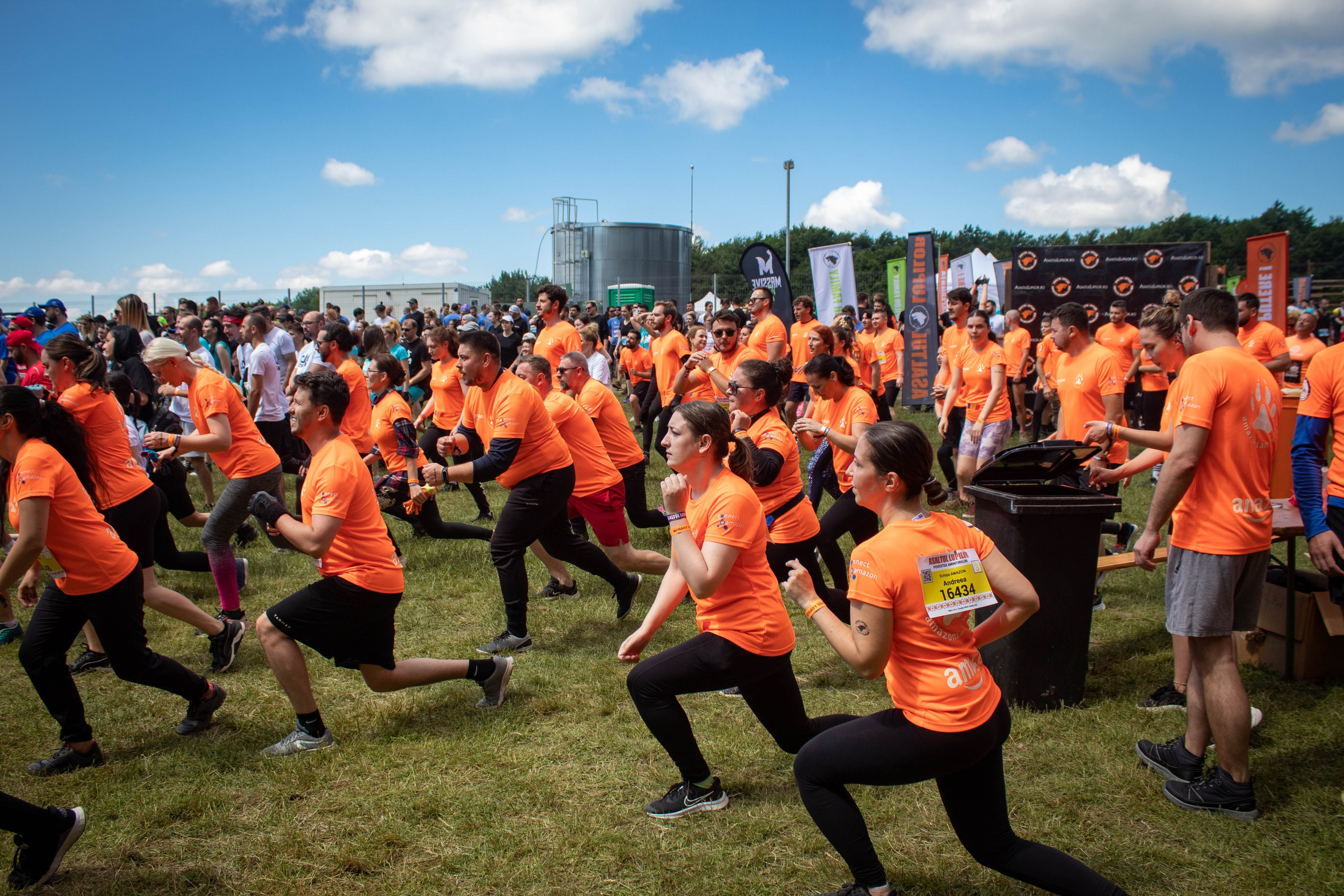 Group of participants doing synchronized warm-up exercises at a sports event.