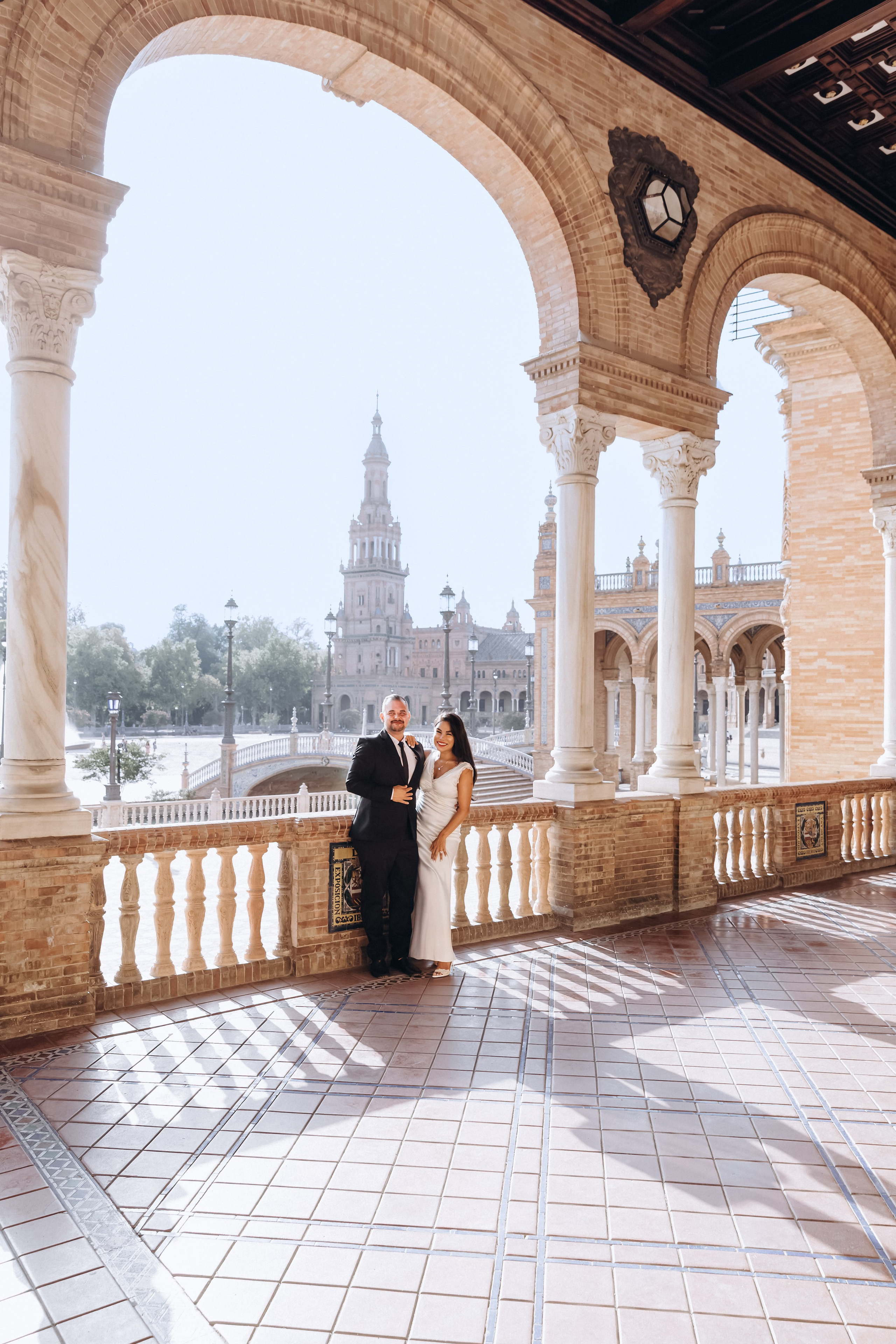 Romantic wedding portrait at Plaza de España in Sevilla, Spain — the couple poses elegantly beneath historic arches with the iconic tower in the background. A perfect choice for couples seeking timeless and architectural wedding photoshoots in Sevilla and southern Spain.