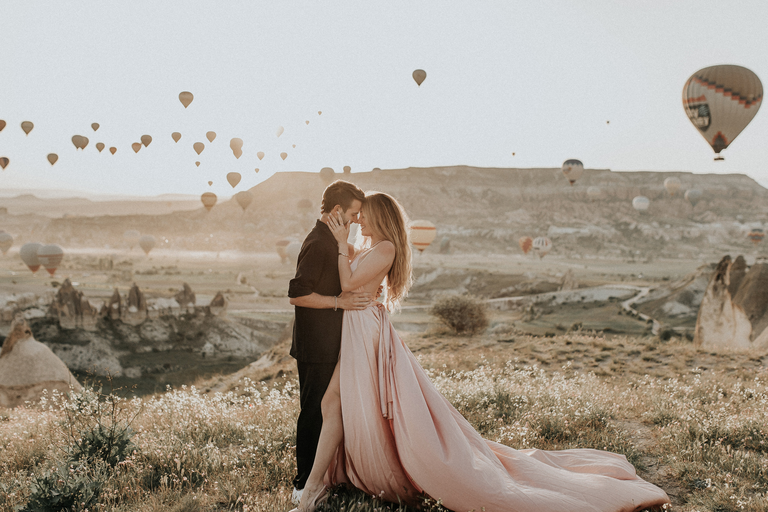 Paarfotografie beim Sonnenaufgang mit Heissluftballons im Hintergrund. Familien- & Hochzeitsfotografin Schweiz. Valeria Diaz in Zürich und Umgebung