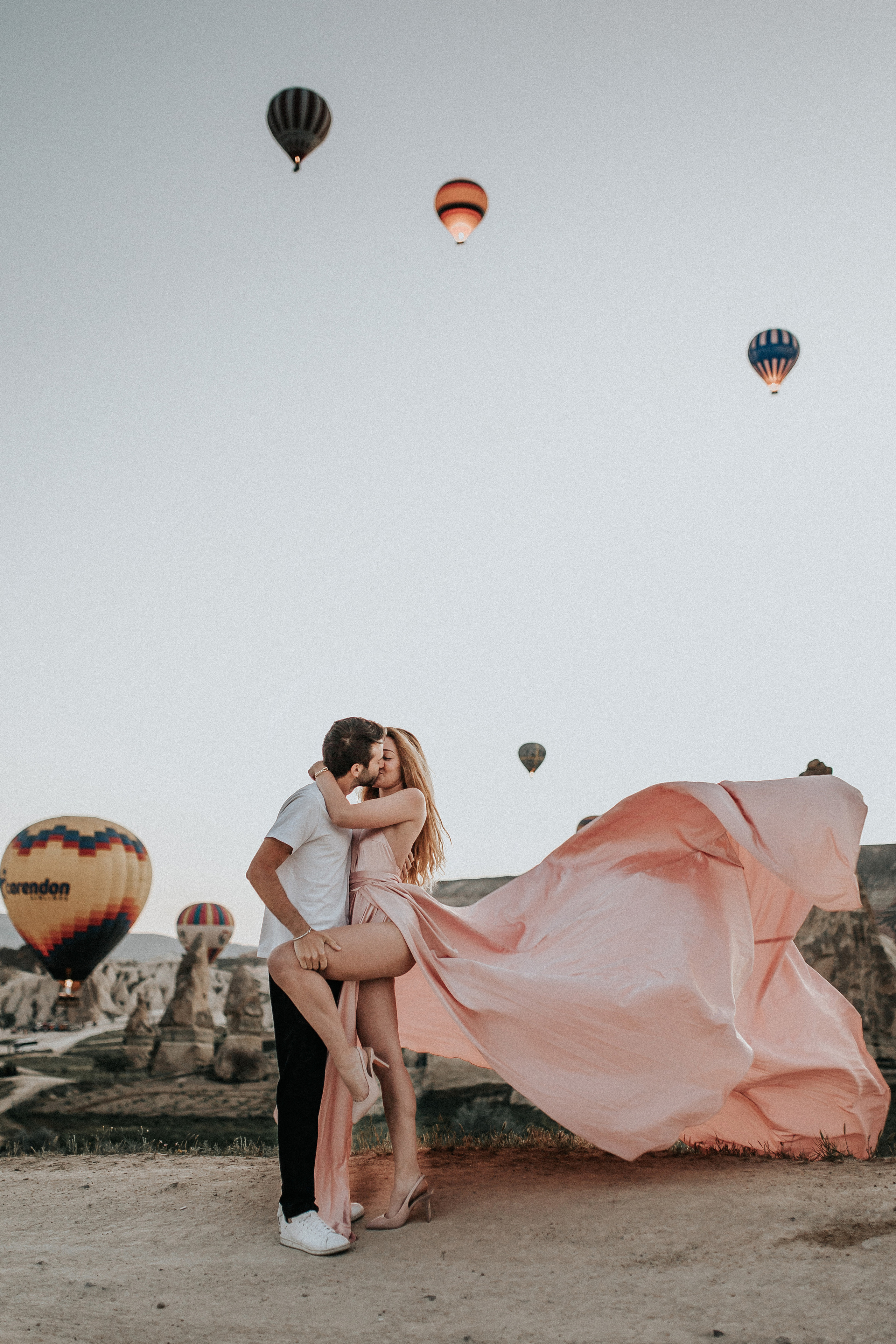 Paarfotografie beim Sonnenaufgang mit Heissluftballons im Hintergrund. Familien- & Hochzeitsfotografin Schweiz. Valeria Diaz in Zürich und Umgebung