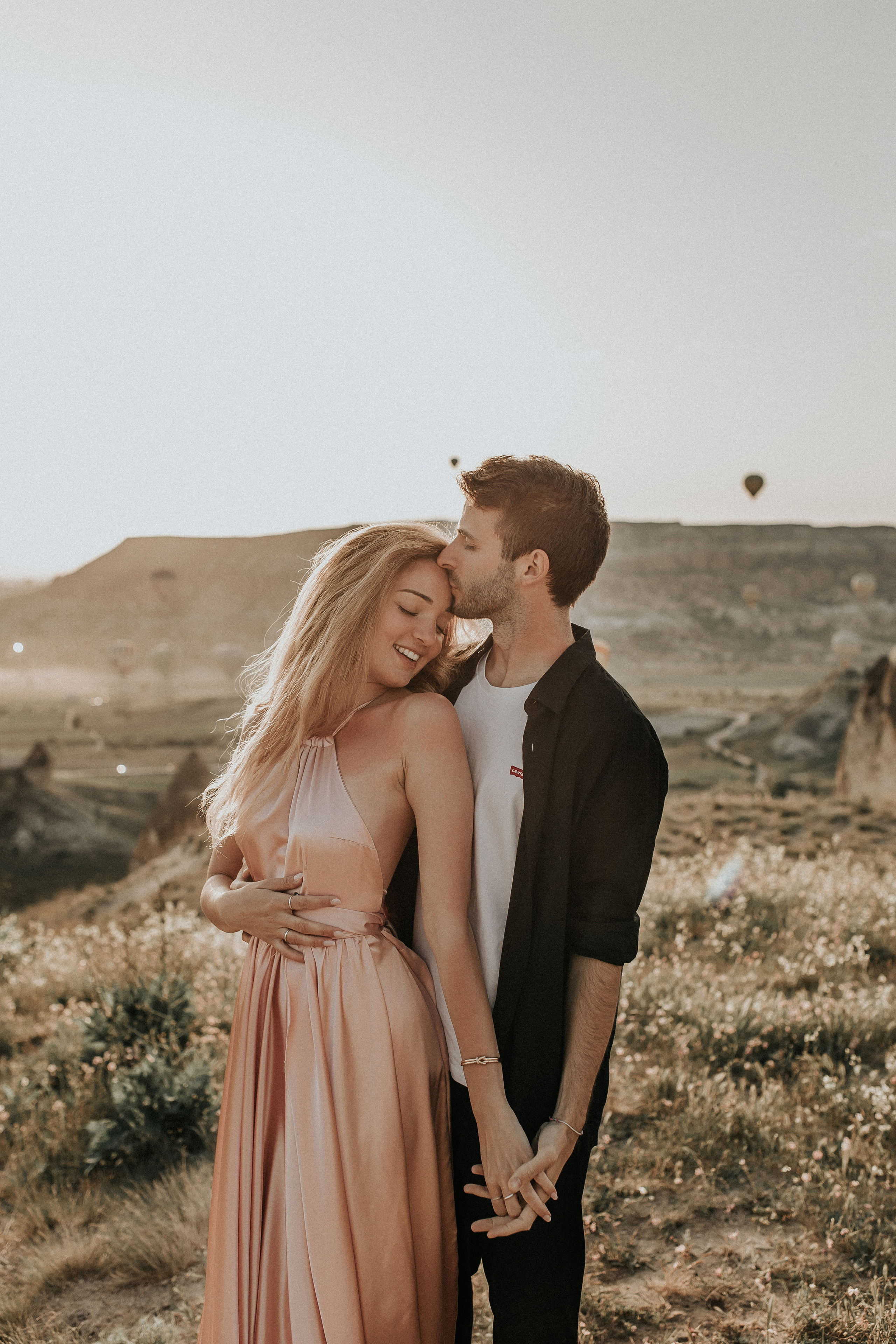 Paarfotografie beim Sonnenaufgang mit Heissluftballons im Hintergrund. Familien- & Hochzeitsfotografin Schweiz. Valeria Diaz in Zürich und Umgebung